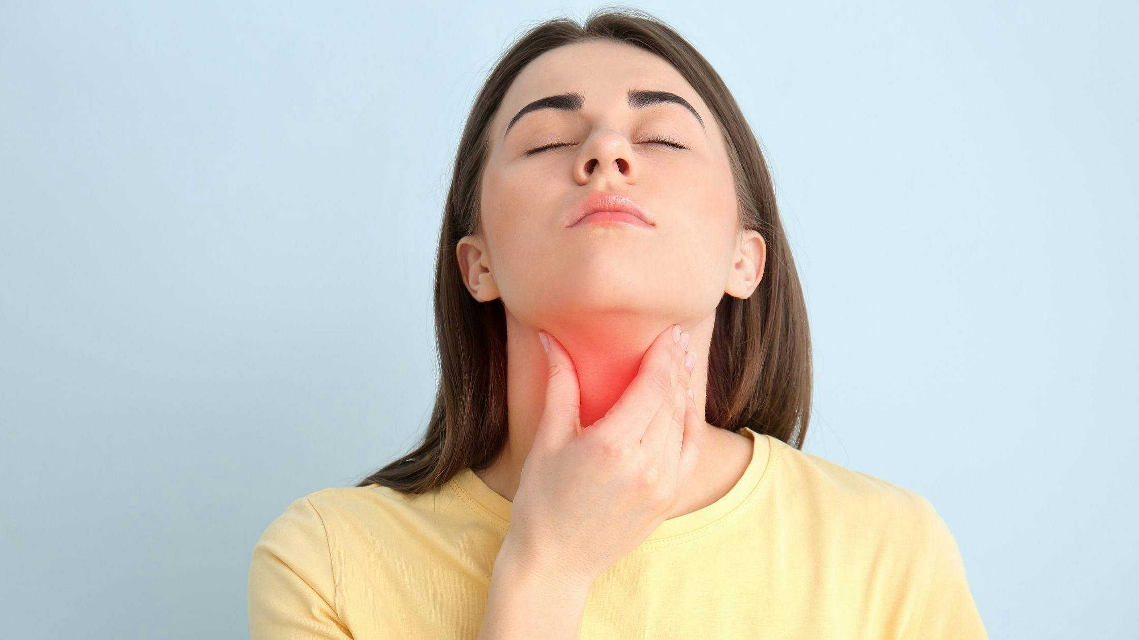 a woman is holding her neck because she has a sore throat .