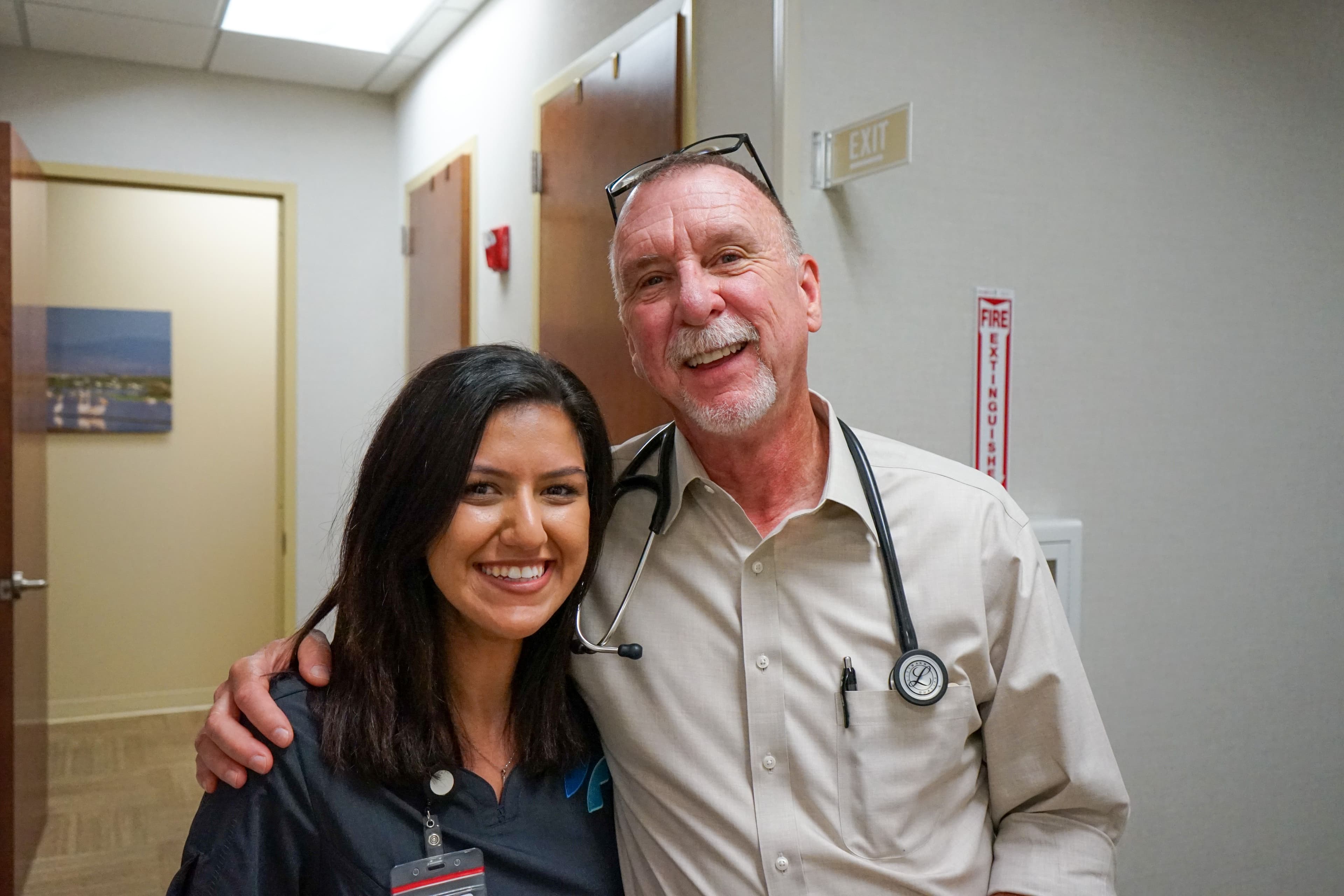 a man and a woman are posing for a picture in a hospital hallway .