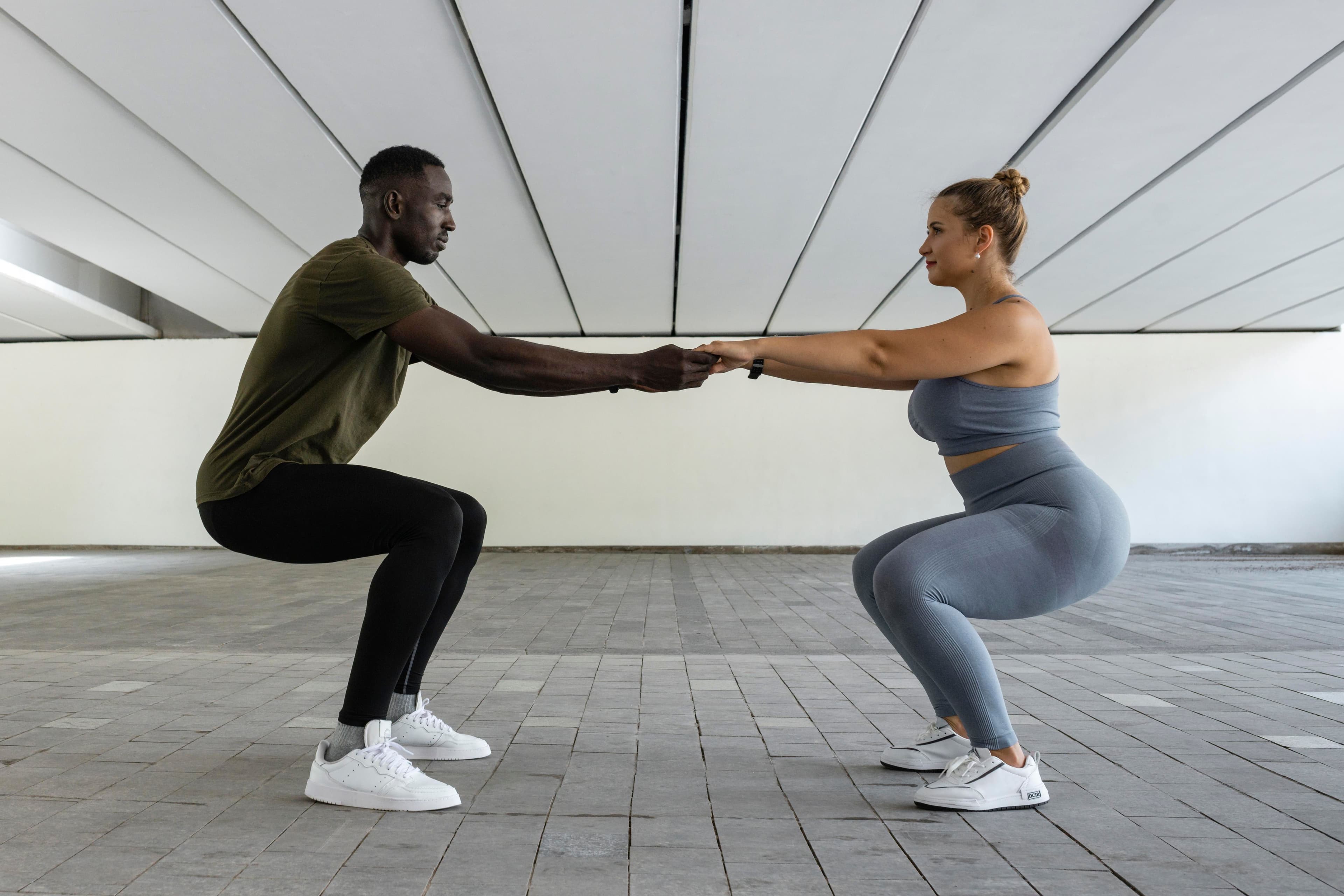 The Power of Exercise: a man and a woman are squatting next to each other and holding hands .