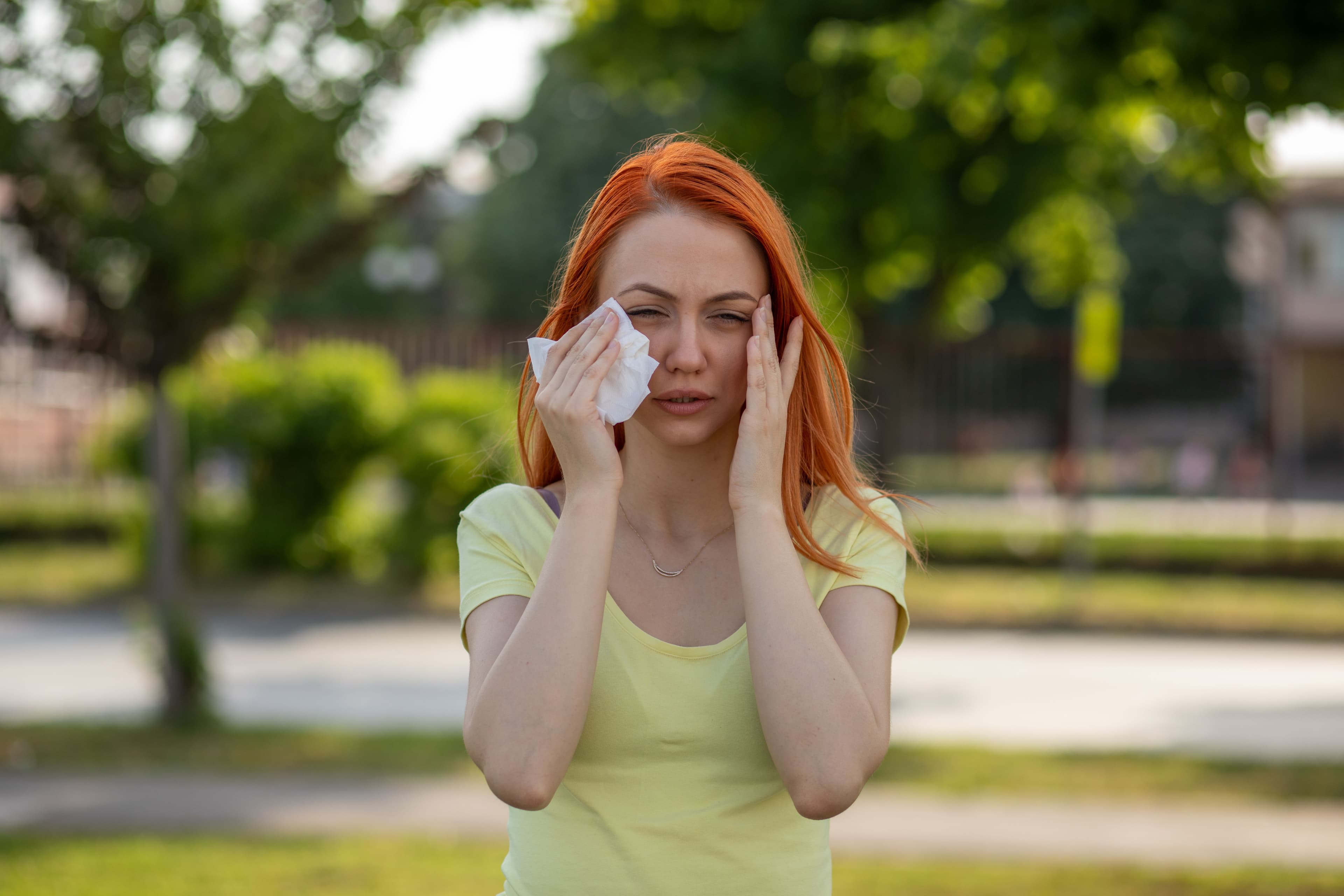 a woman with red hair is blowing her nose with a napkin .