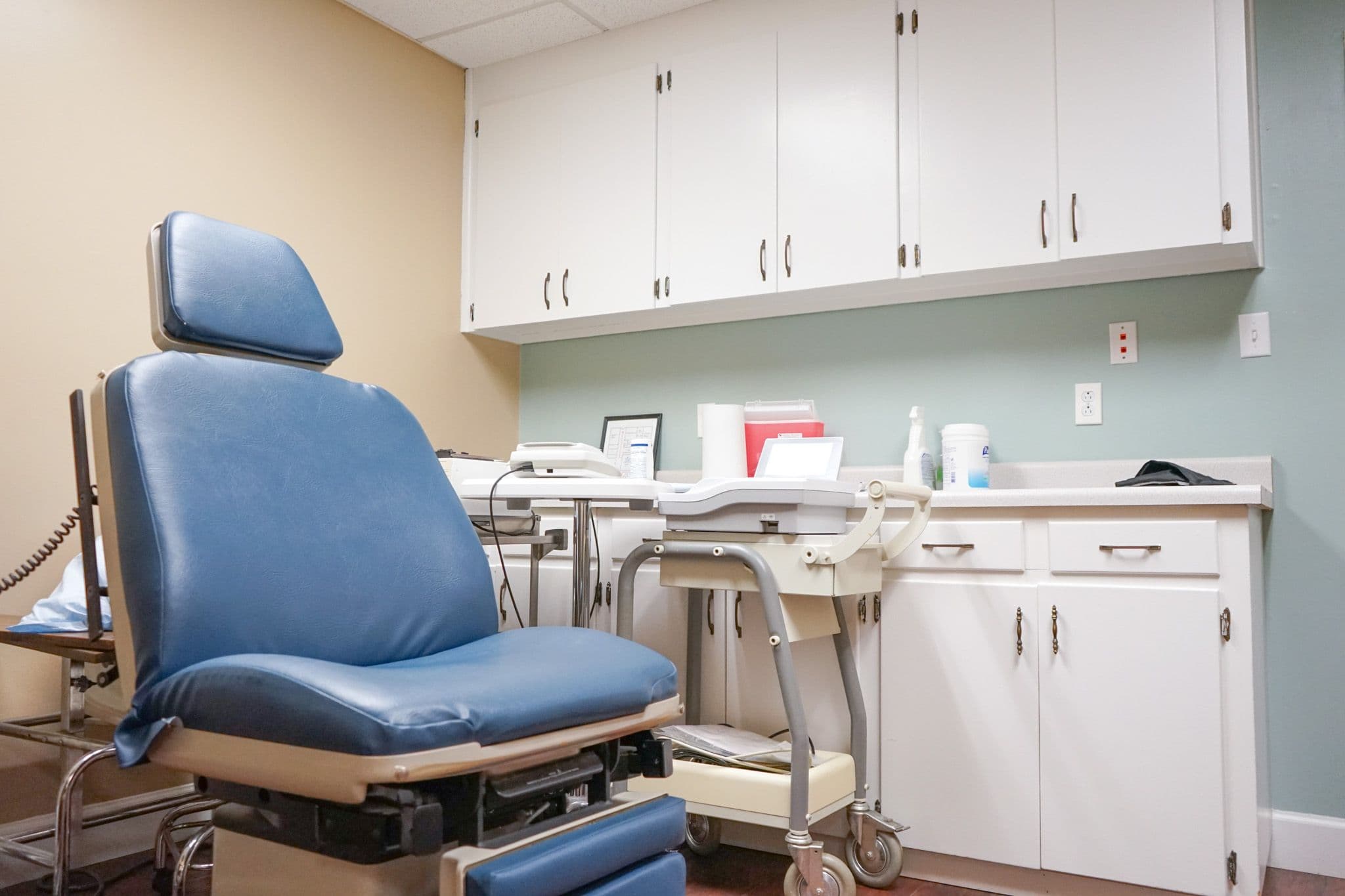 there is a blue chair in the middle of the Middle Georgia Primary Care exam room .