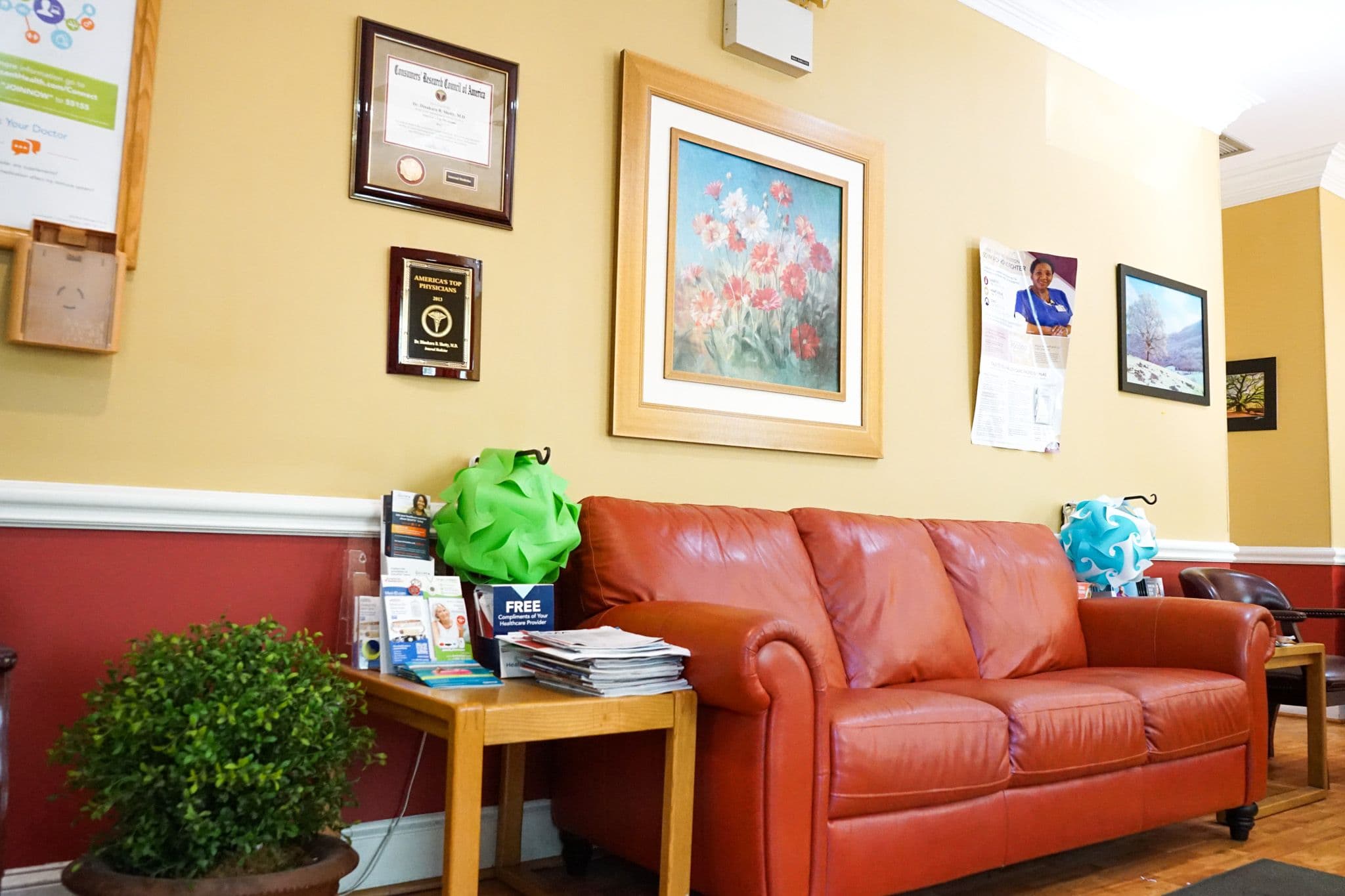 there is a red couch in the waiting room of a dental office .