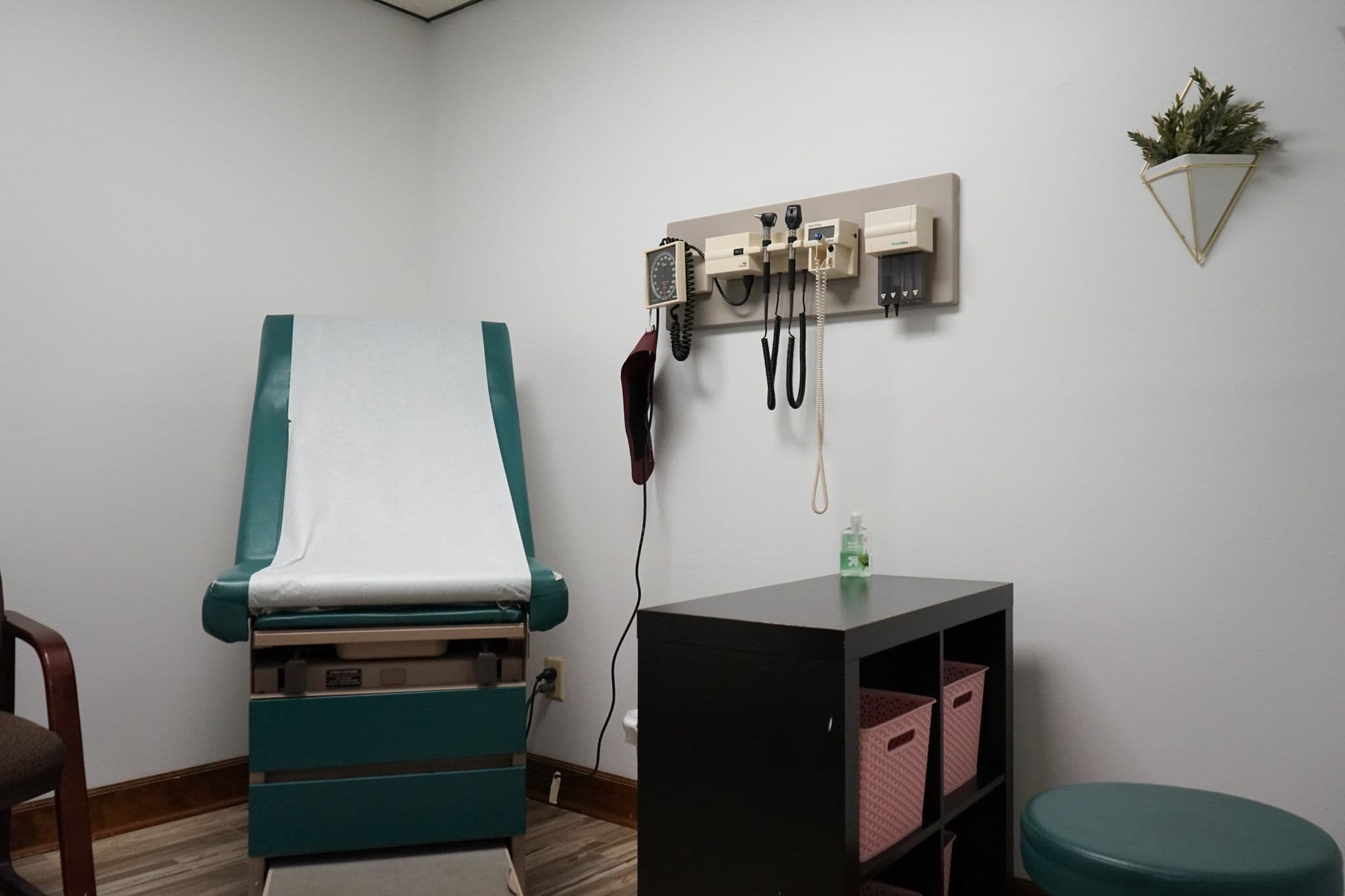 a doctor 's office with a green exam table and a stool .