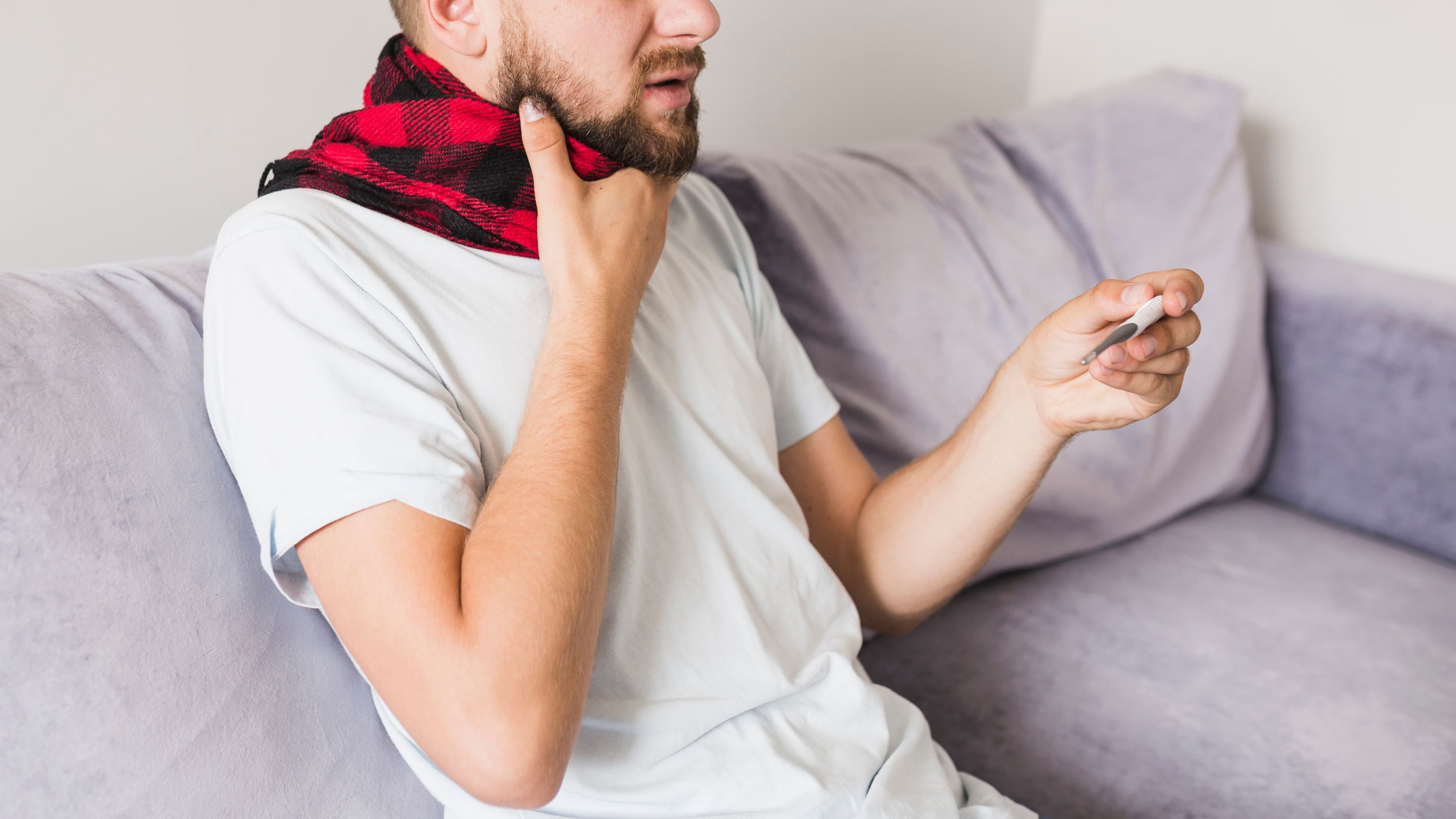 globus pharyngeus: a man is sitting on a couch with a thermometer in his hand .