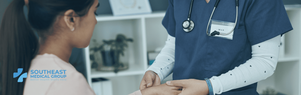 A doctor in blue scrubs holds a patient's hand.