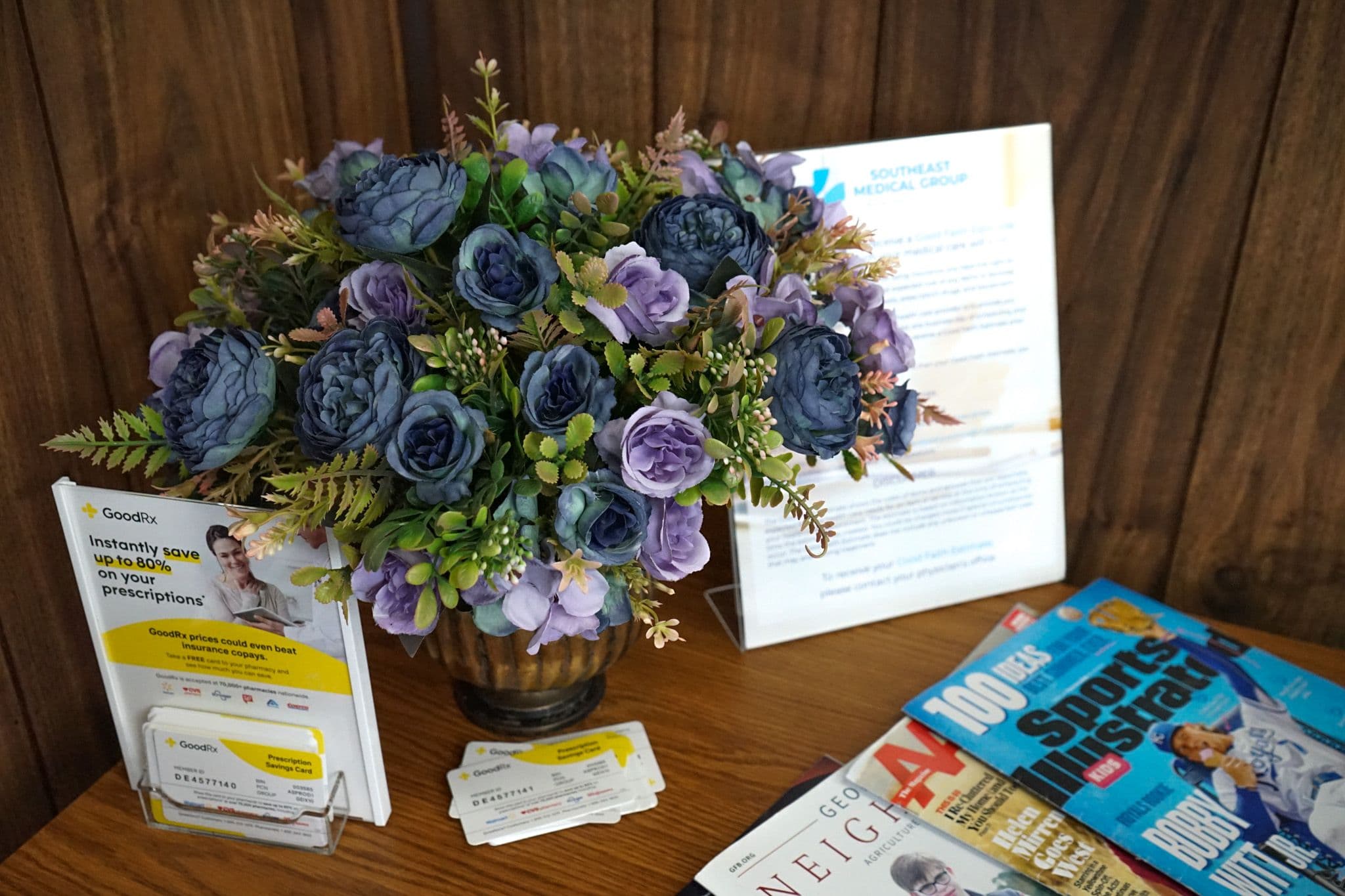 a vase of purple flowers is sitting on a table next to a magazine .