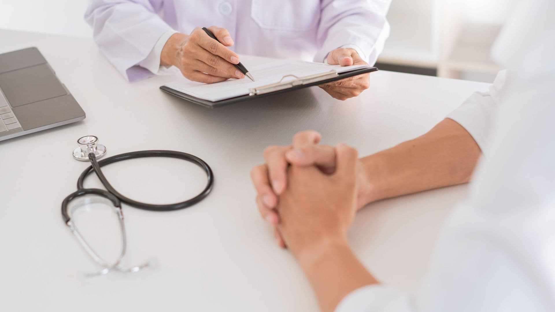 Doctor writing on a clipboard during a patient consultation.