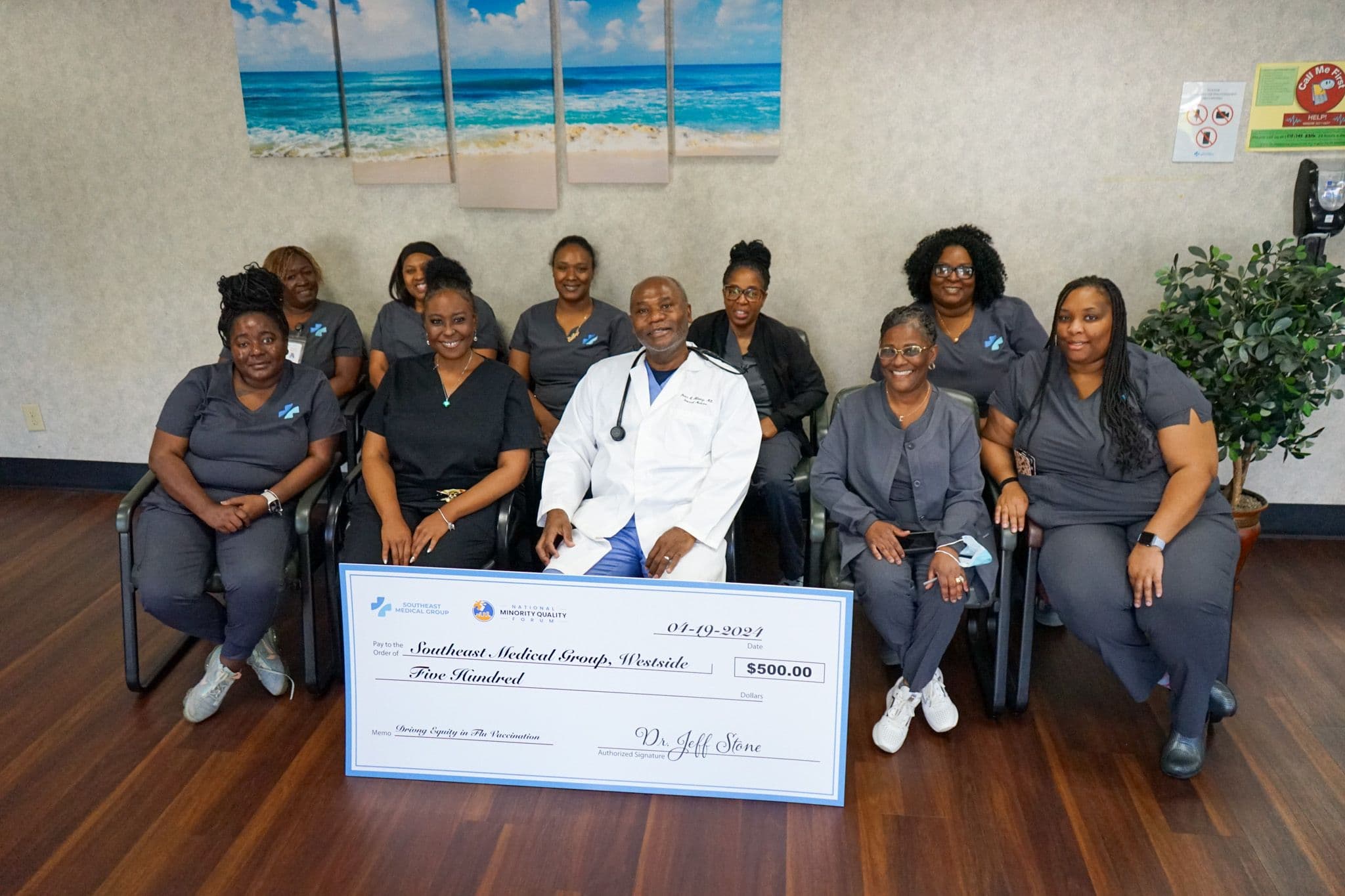 A group of medical professionals, including a doctor, smile while holding a large $500 check for Southeast Medical Group, Westside.