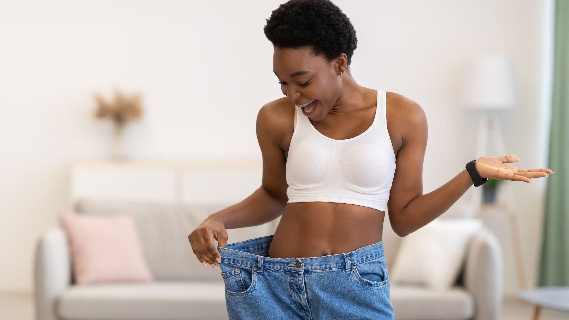 a woman is standing in a living room wearing a pair of oversized jeans .