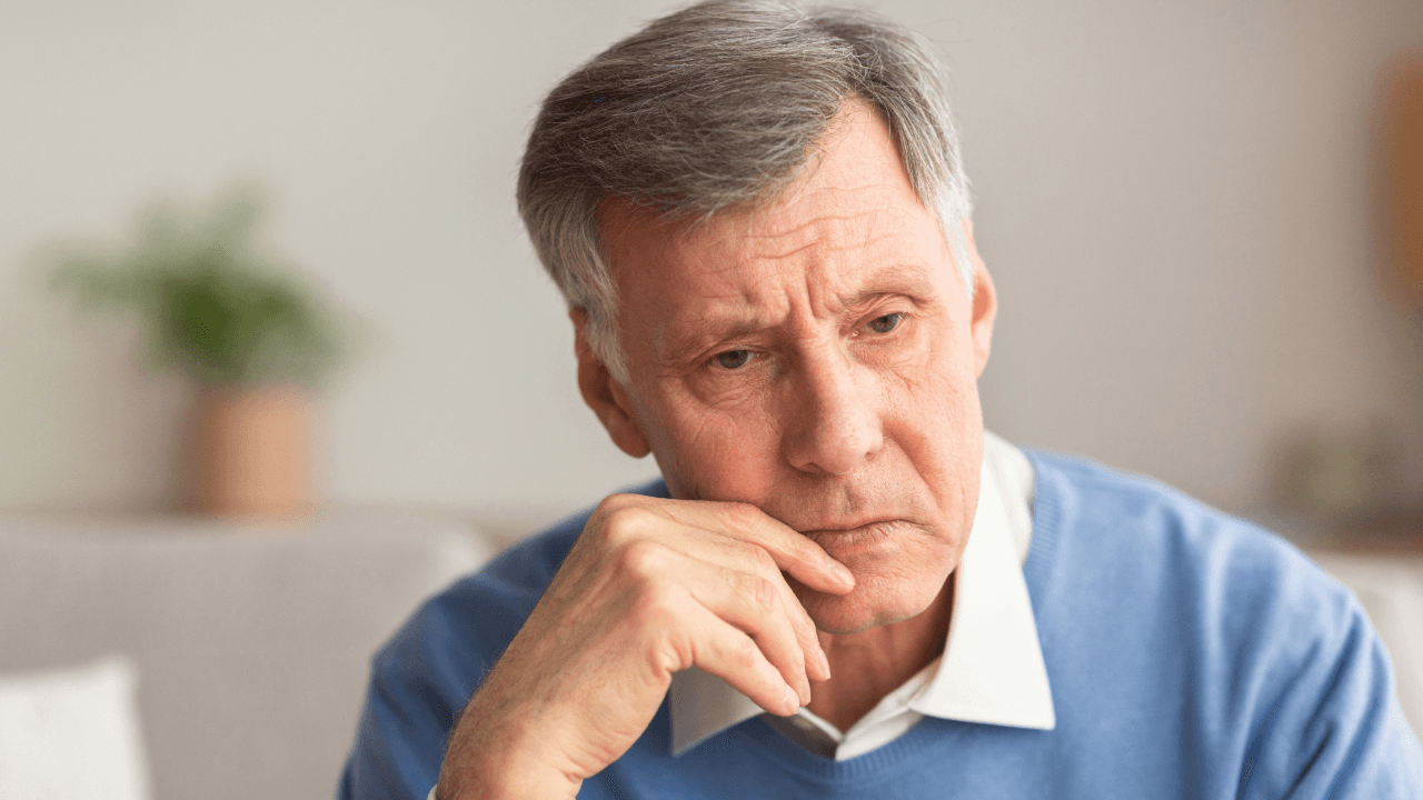 dementia: a man in a blue sweater has his hand on his chin