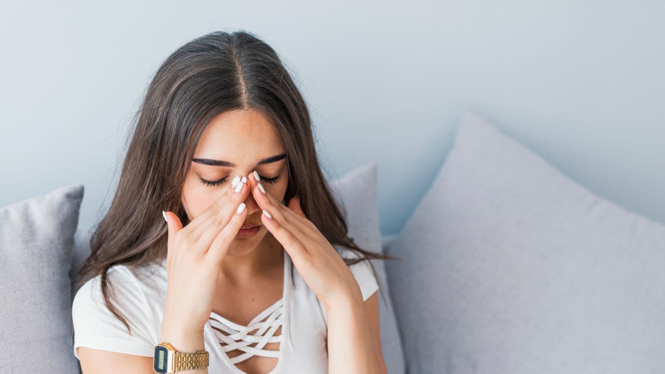 a woman is sitting on a couch covering her face with her hands .