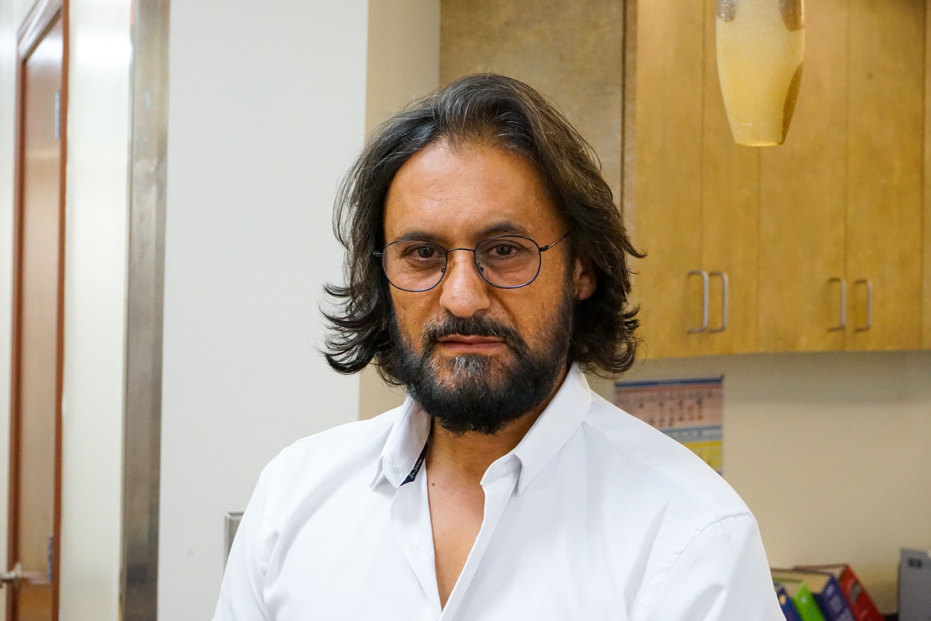 a man with a beard and glasses is wearing a white shirt .