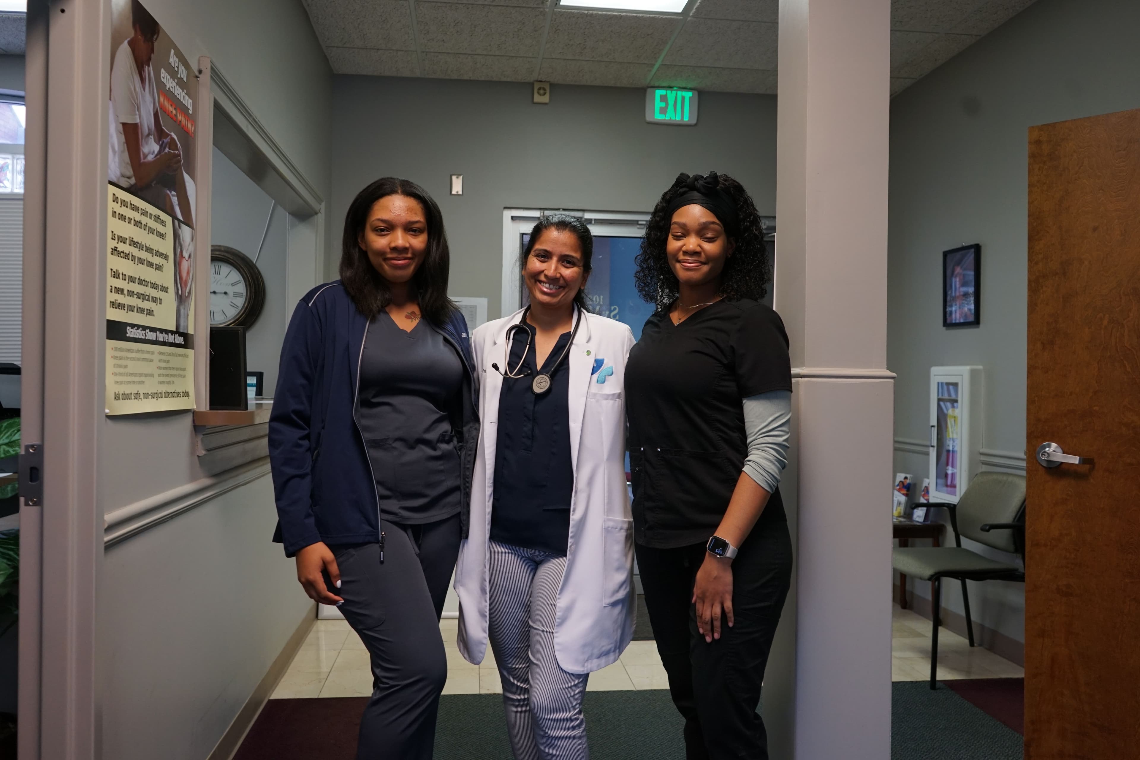 three female doctors are standing next to each other in a hallway .