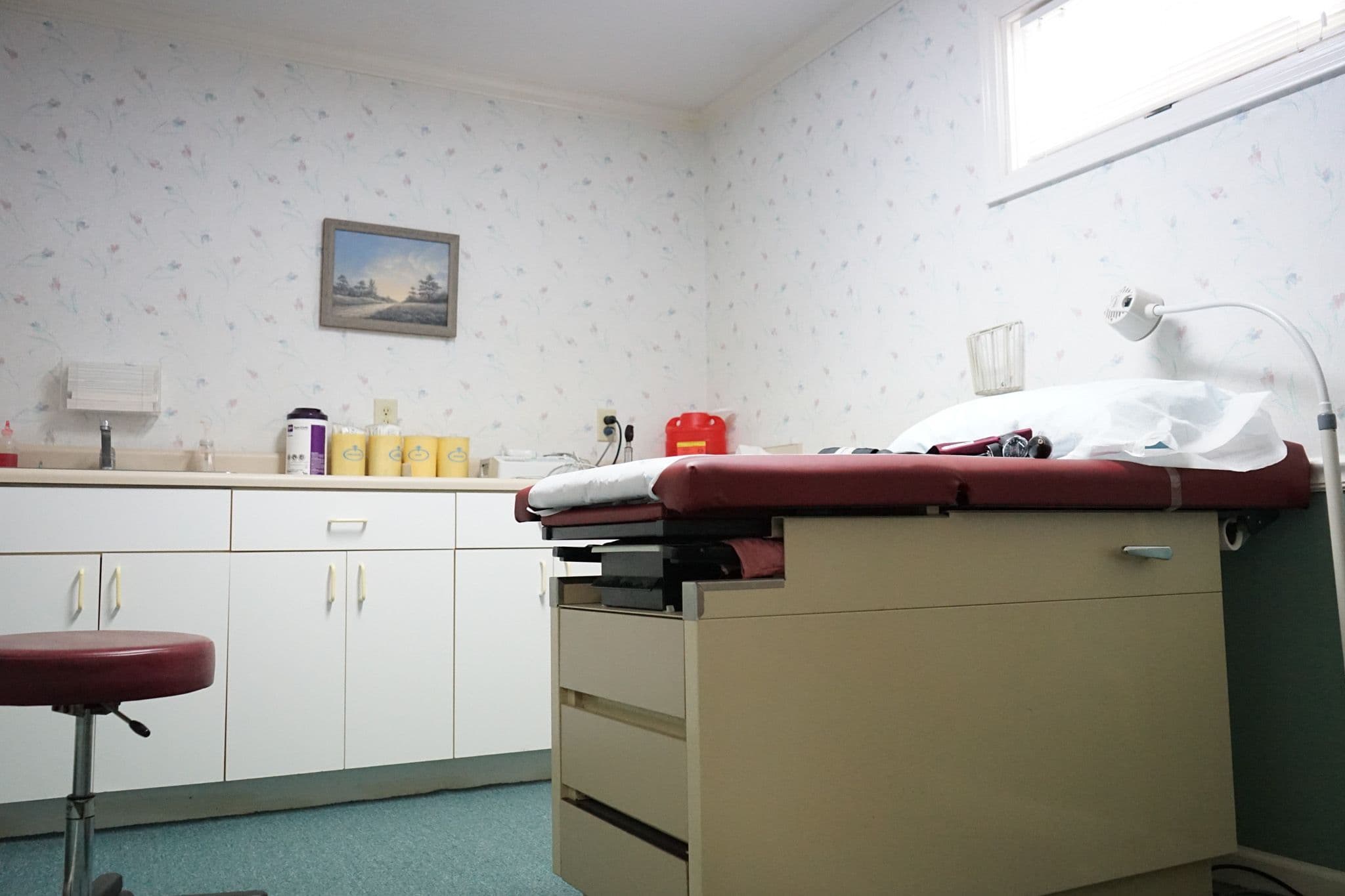 a doctor 's office with a red examination table and a red stool .