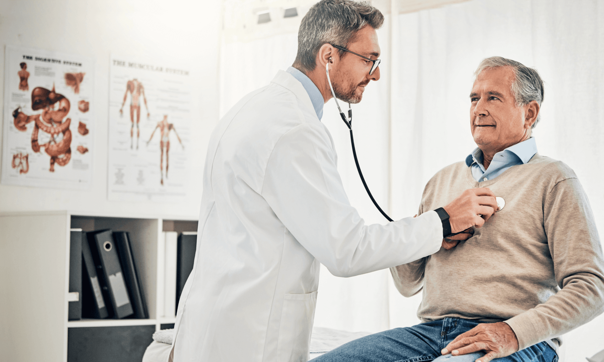 A male doctor examines an older male patient with a stethoscope.