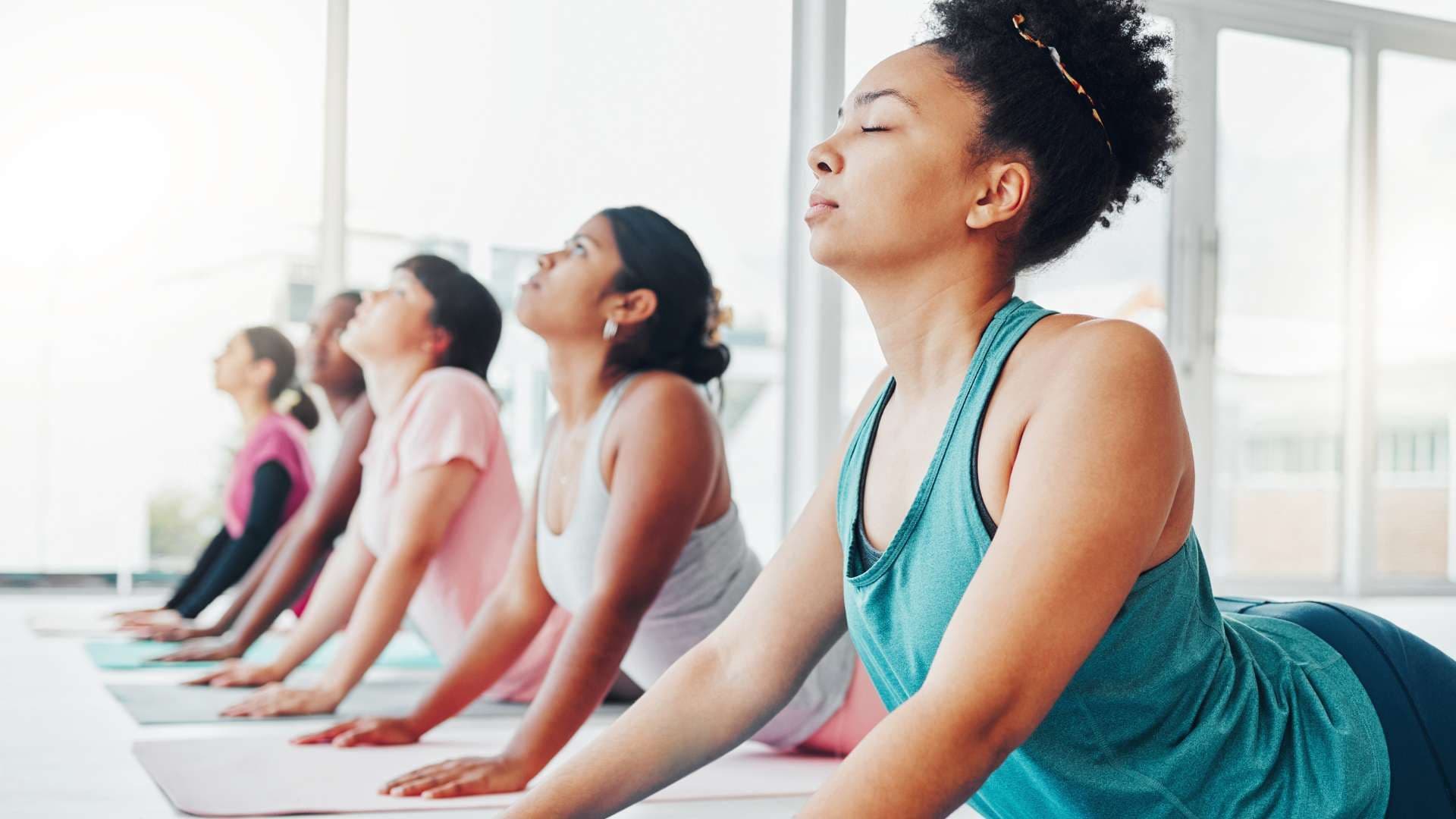 a group of women are doing yoga together in a gym .