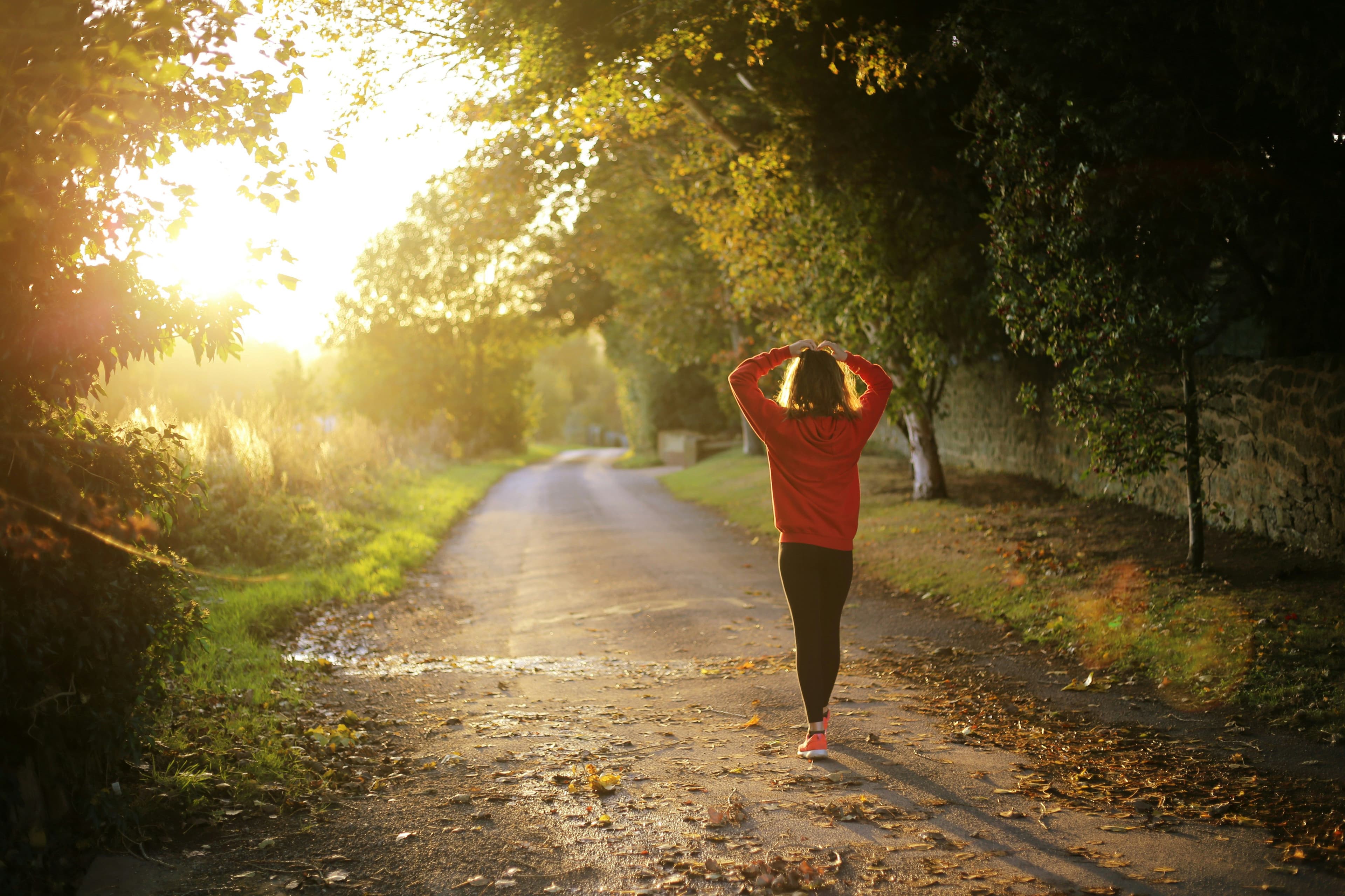 a woman is walking down a road at sunset .
