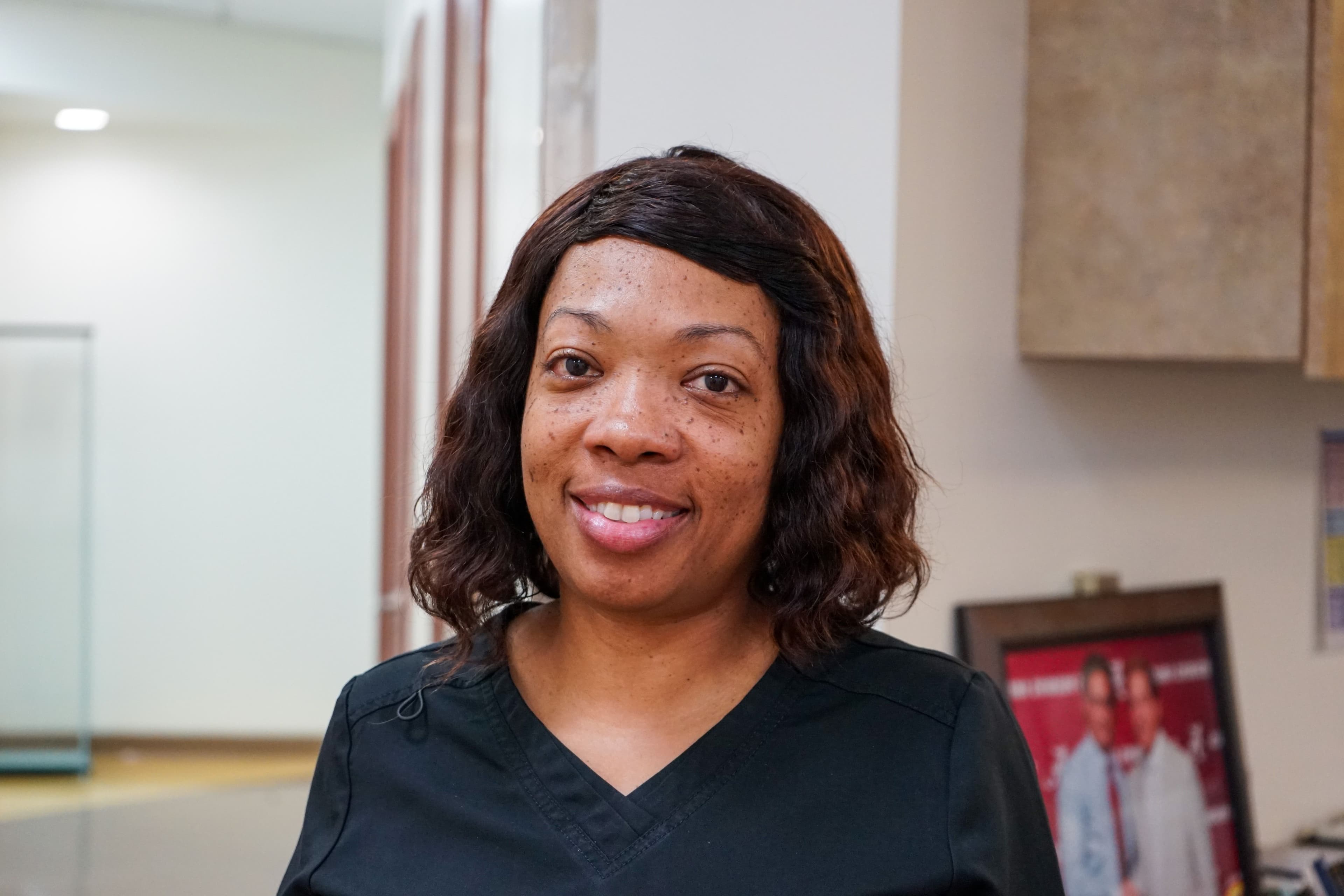 a woman in a black scrub top is smiling for the camera .