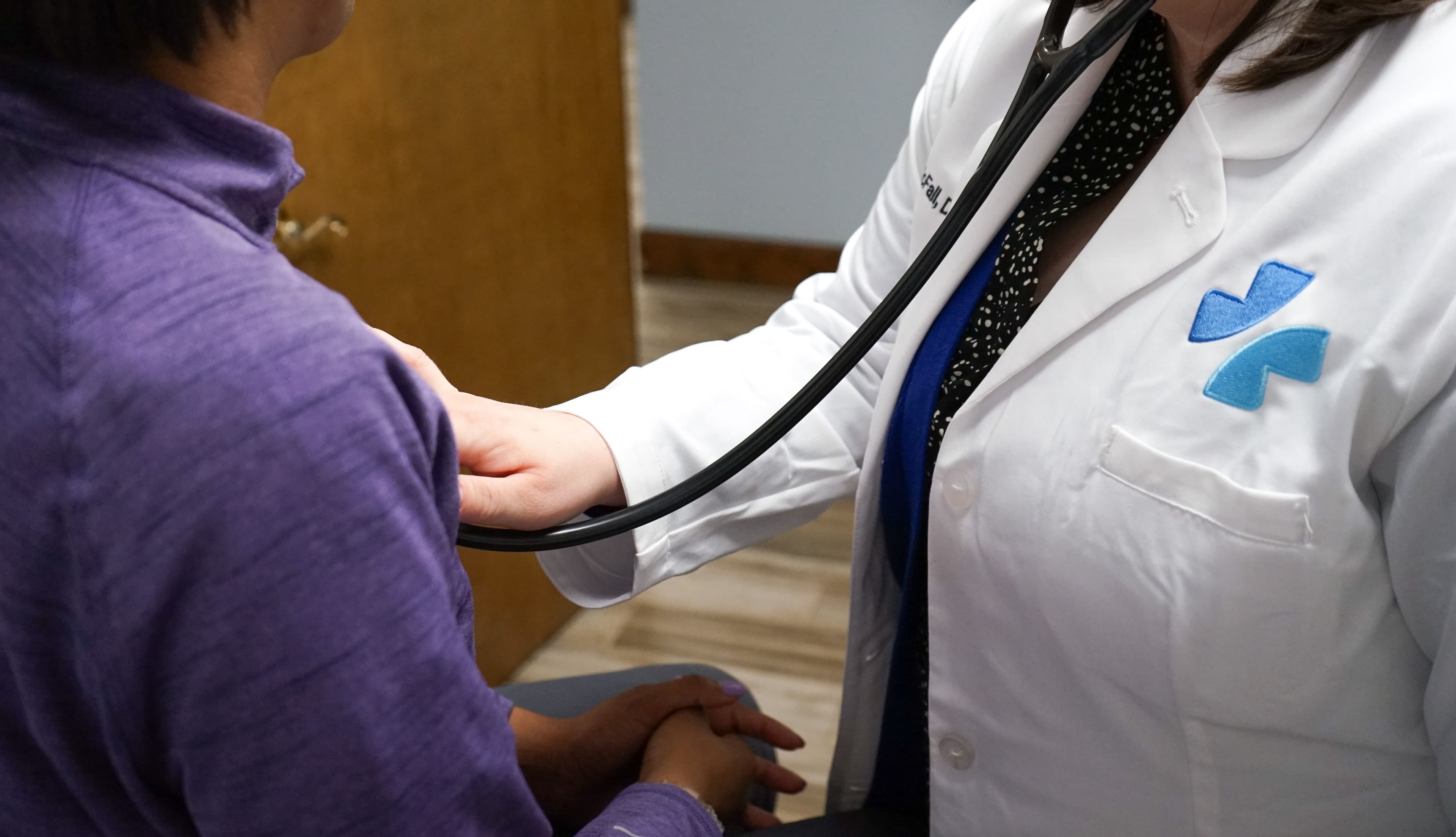 a doctor is listening to a patient 's heart with a stethoscope .