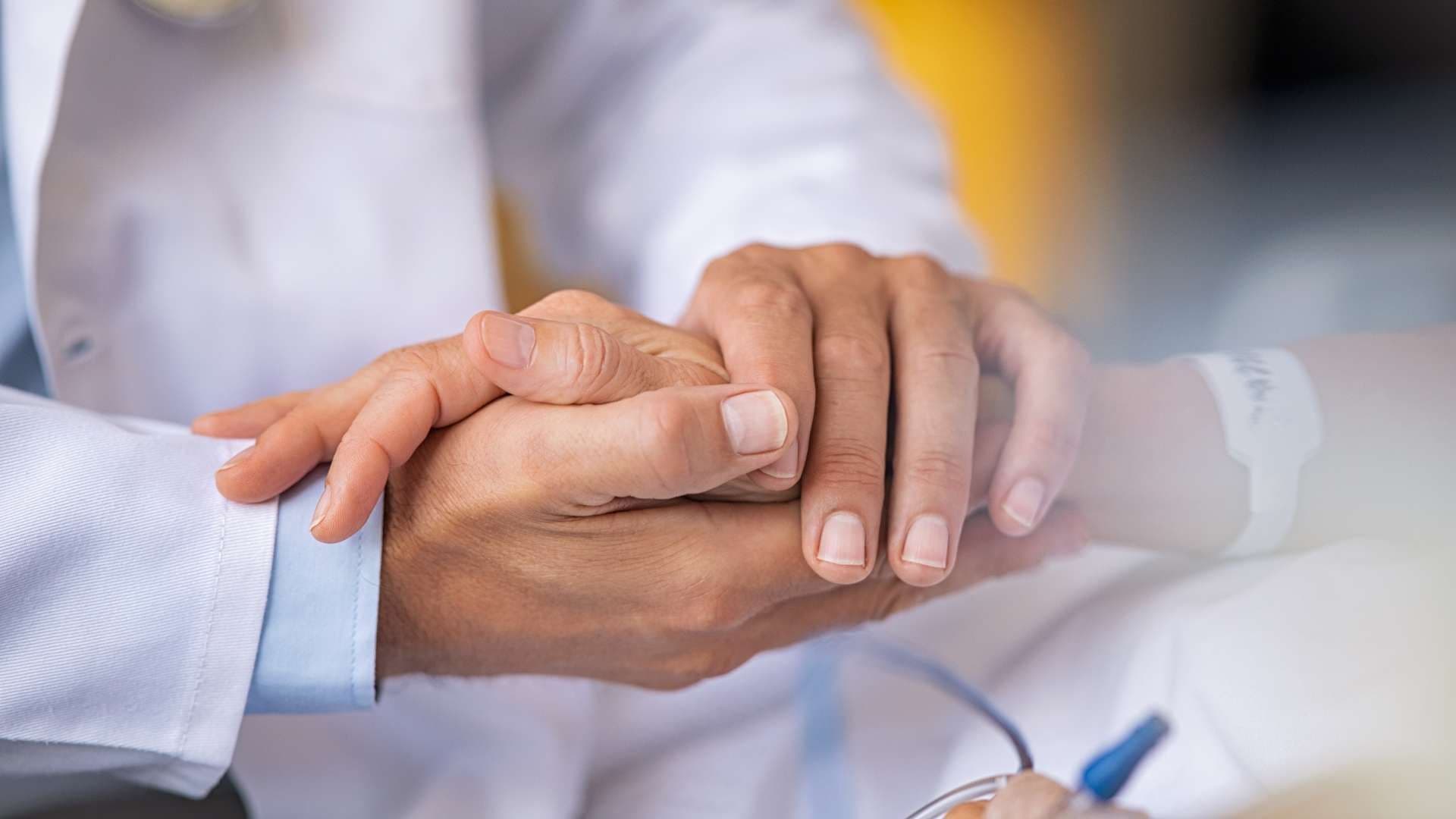 a doctor is holding the hand of a patient .