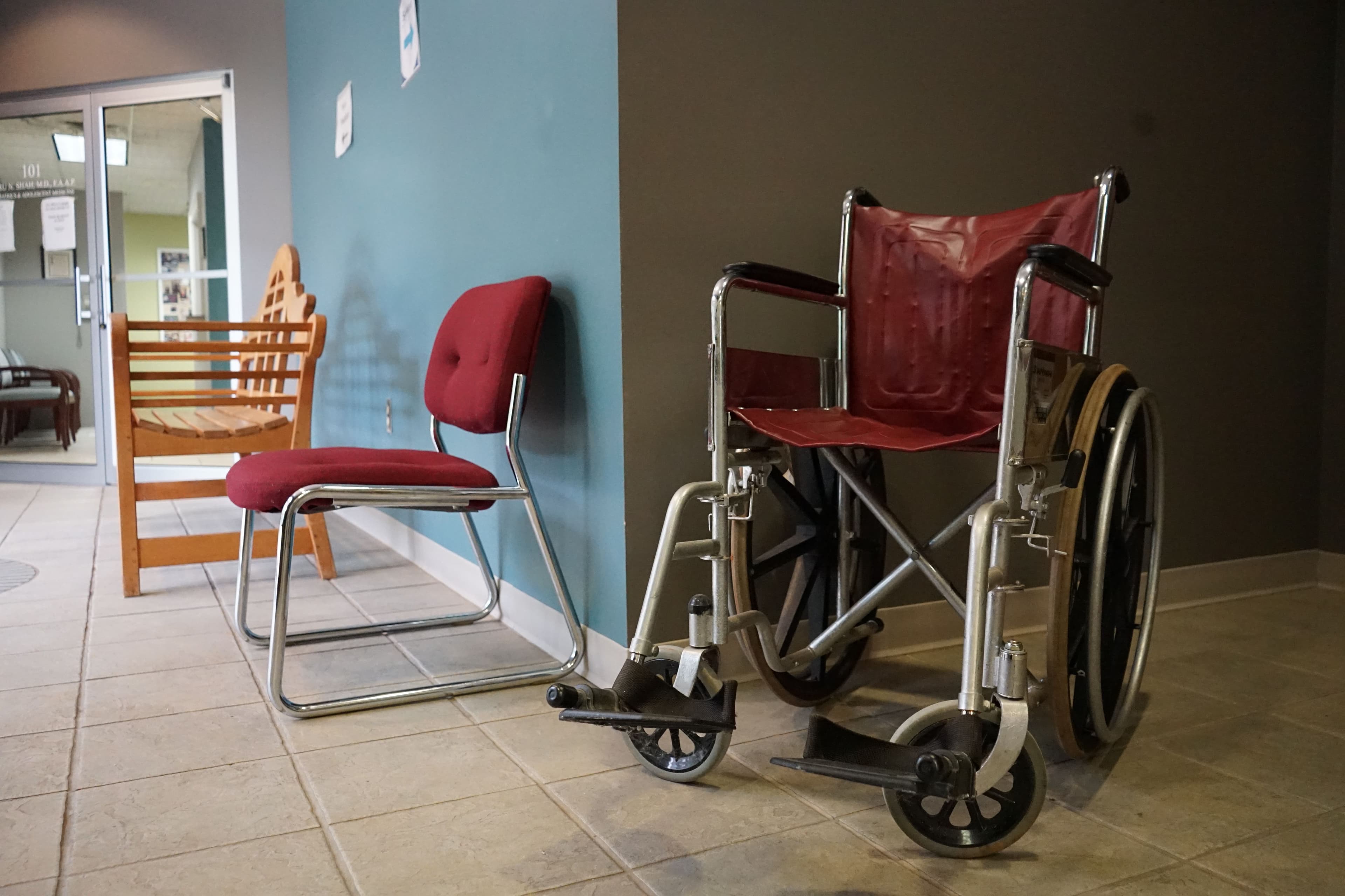 a wheelchair is sitting next to a chair in a hallway .