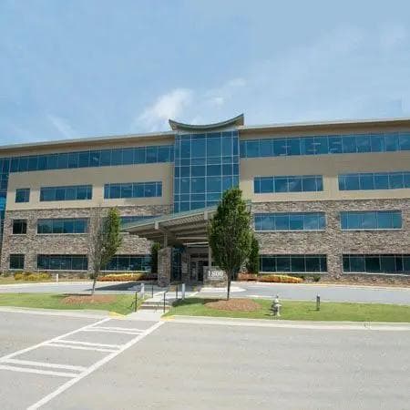 Large modern building with stone and tan exterior, numerous windows, and a covered main entrance.