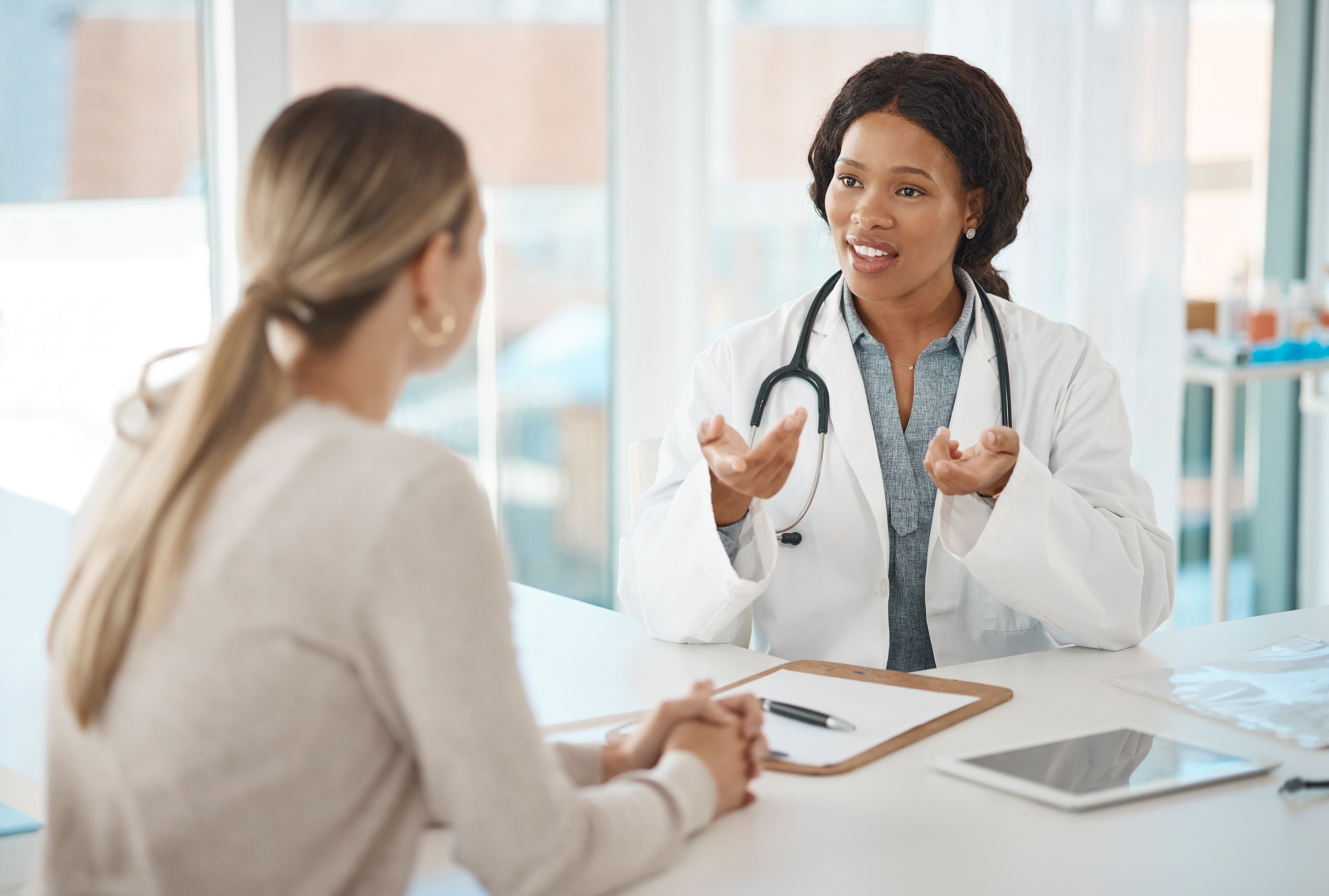a doctor is talking to a patient at a desk in a hospital .