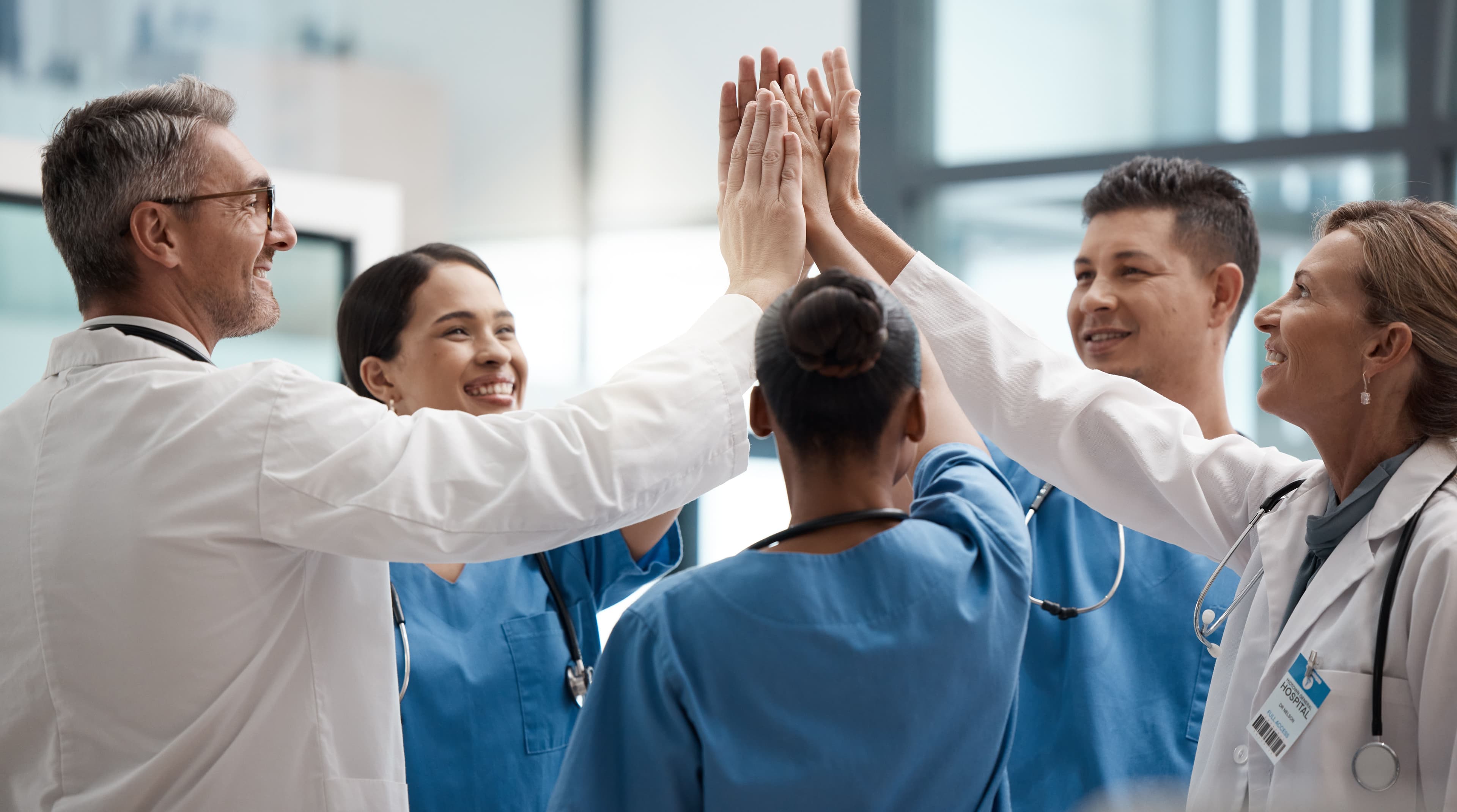 a group of doctors and nurses are giving each other a high five .