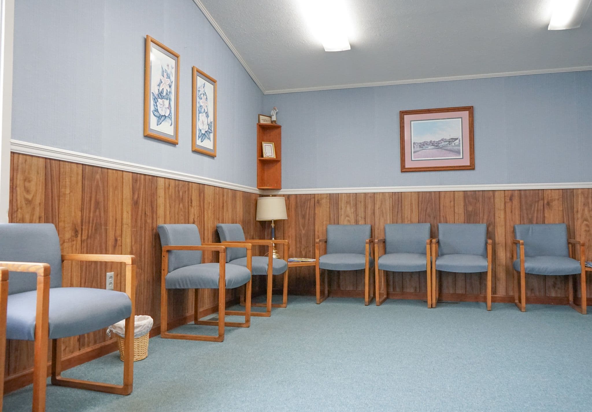 a waiting room with blue chairs and wood paneling on the walls .