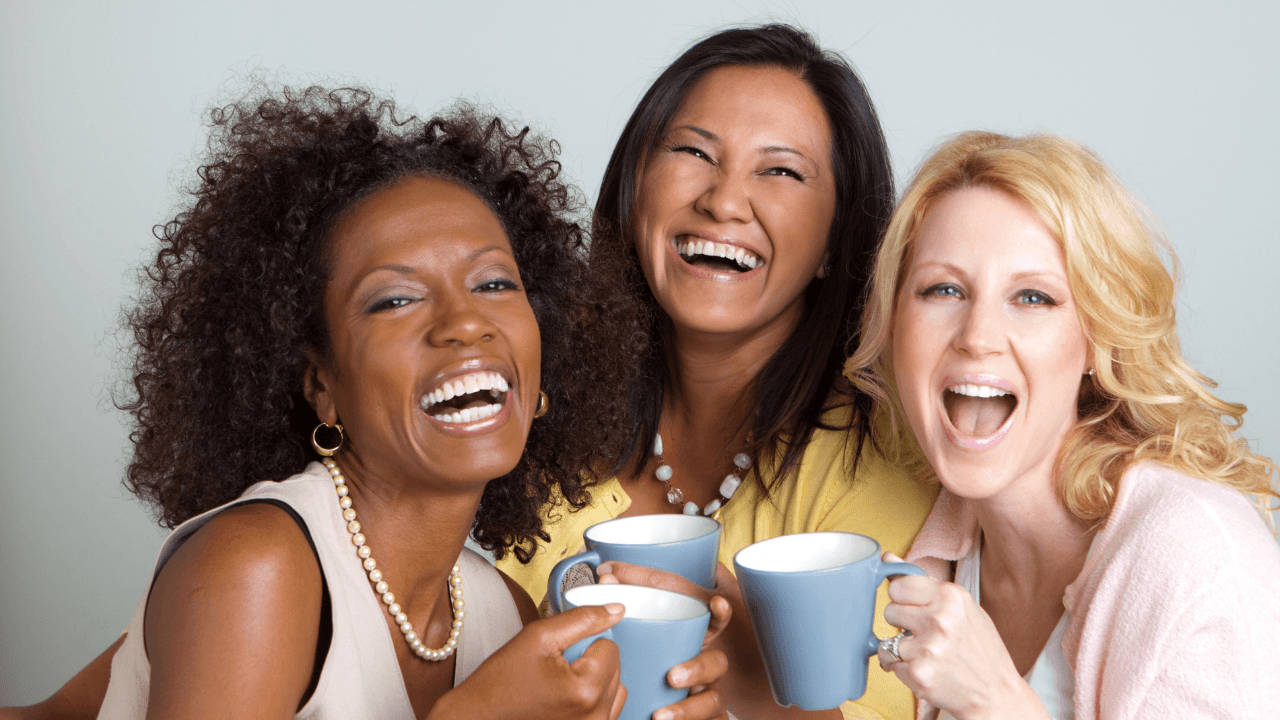 Women's Health: Three women of different ethnicities laugh while holding coffee mugs.