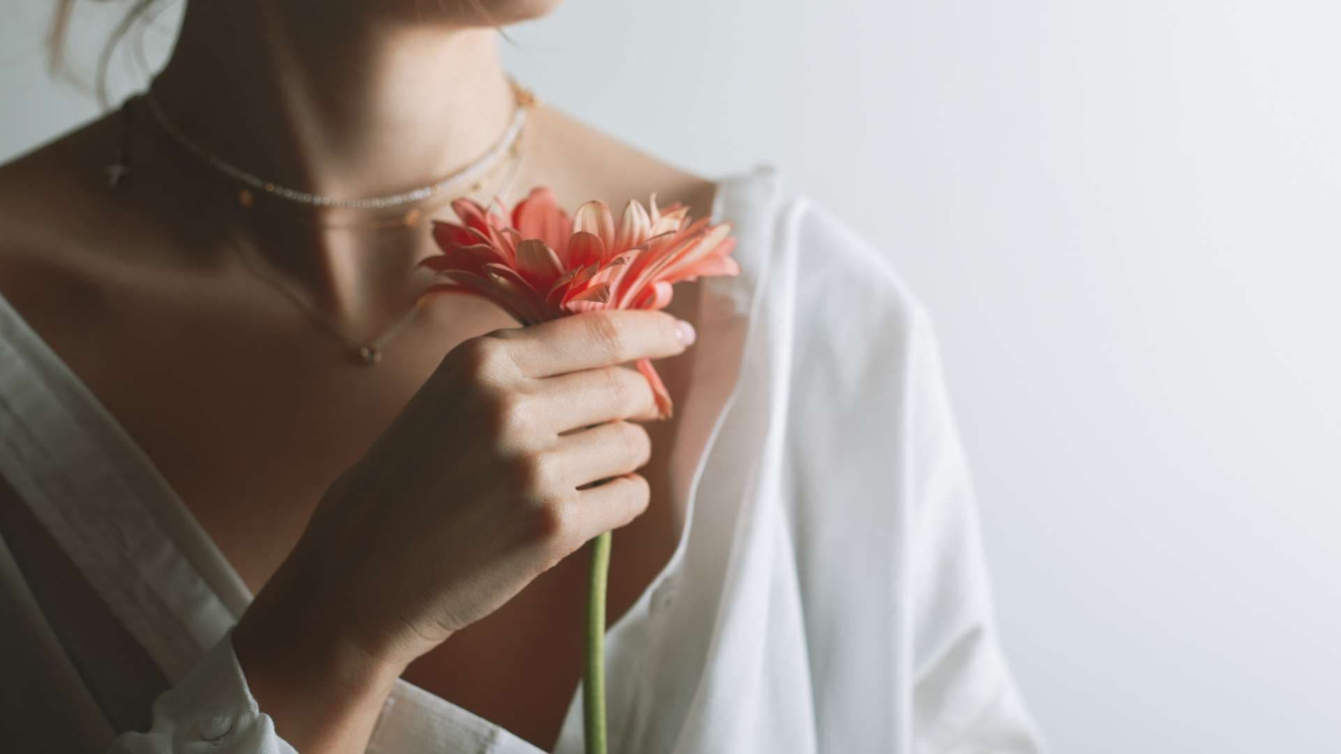 a woman is holding a flower in her hand .