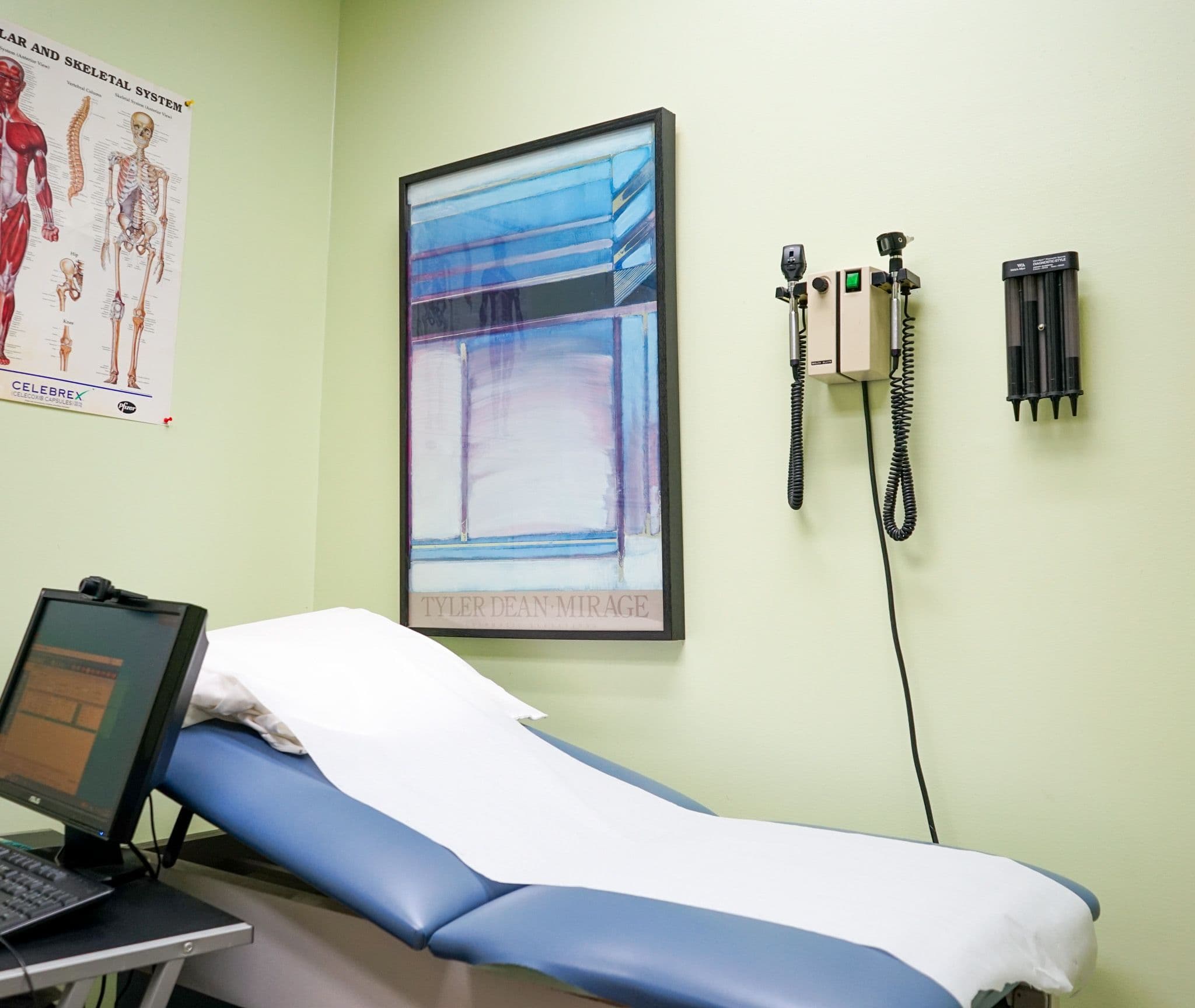 a doctor 's office with a blue exam table and a laptop .