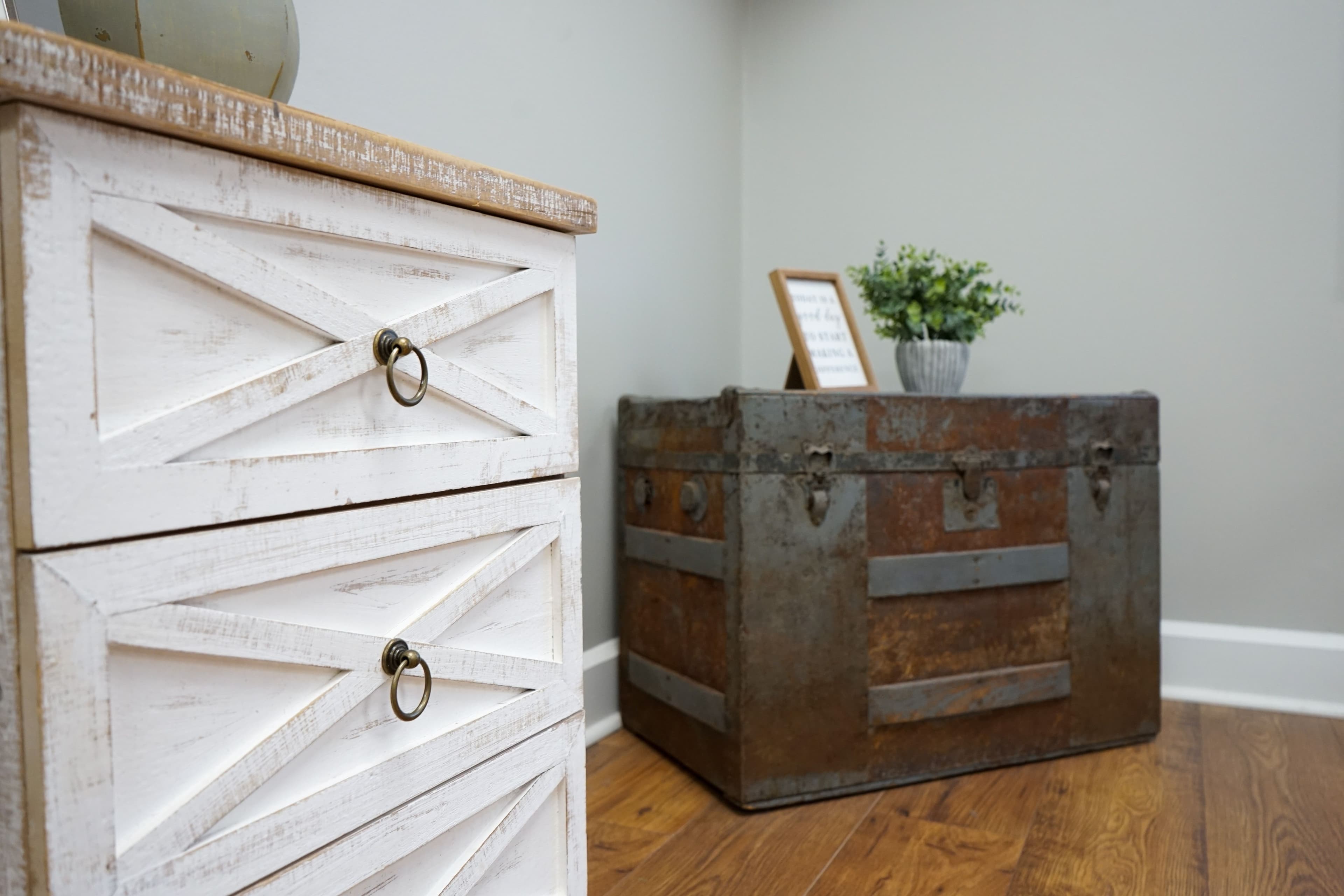 a wooden trunk is sitting next to a white dresser in a room .