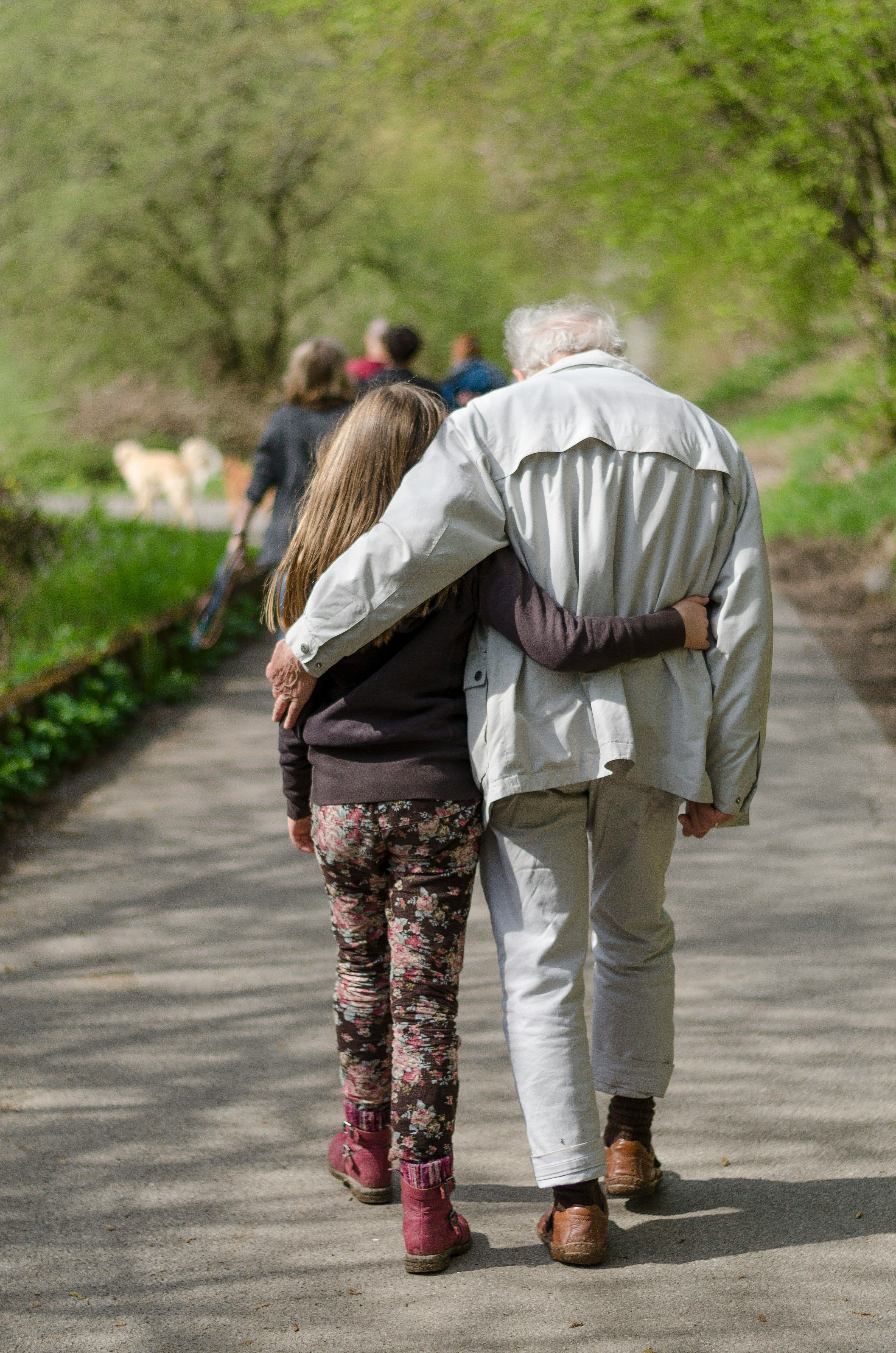 a man and a little girl are walking down a path