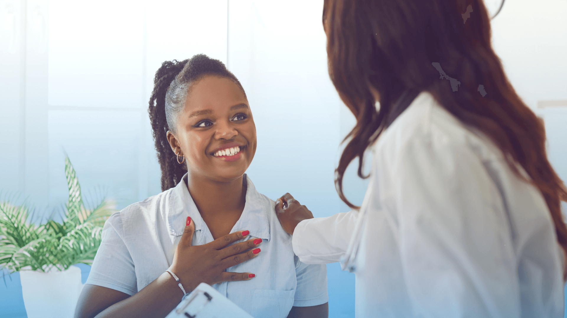 A smiling patient with her hand on her chest is comforted by a doctor.