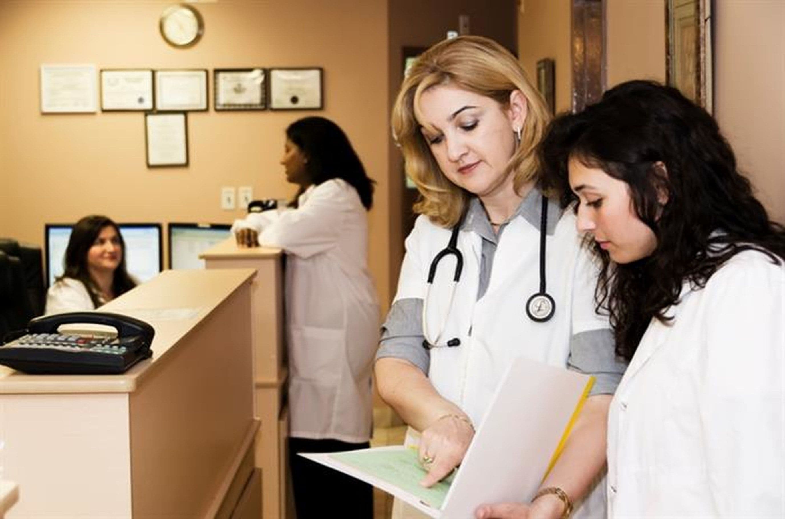 a group of doctors are standing in a hospital lobby looking at papers .