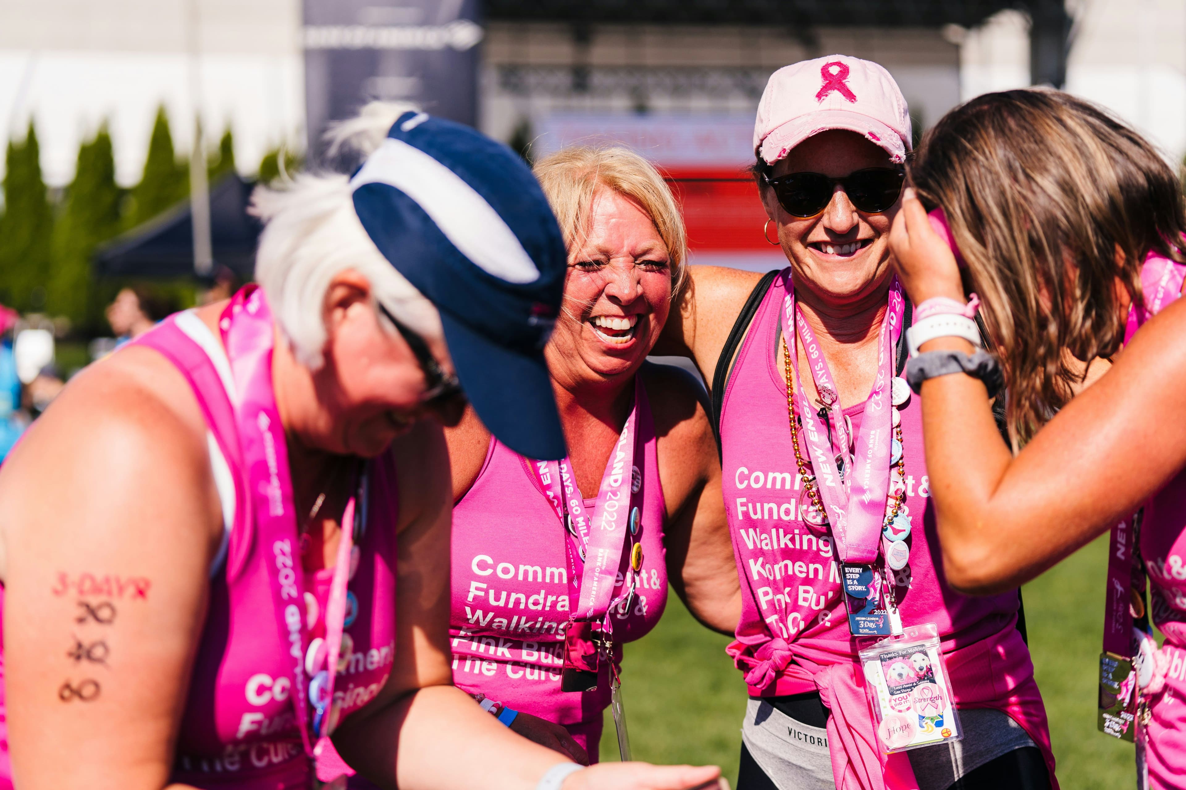 a group of women wearing pink tank tops are standing next to each other in a field .