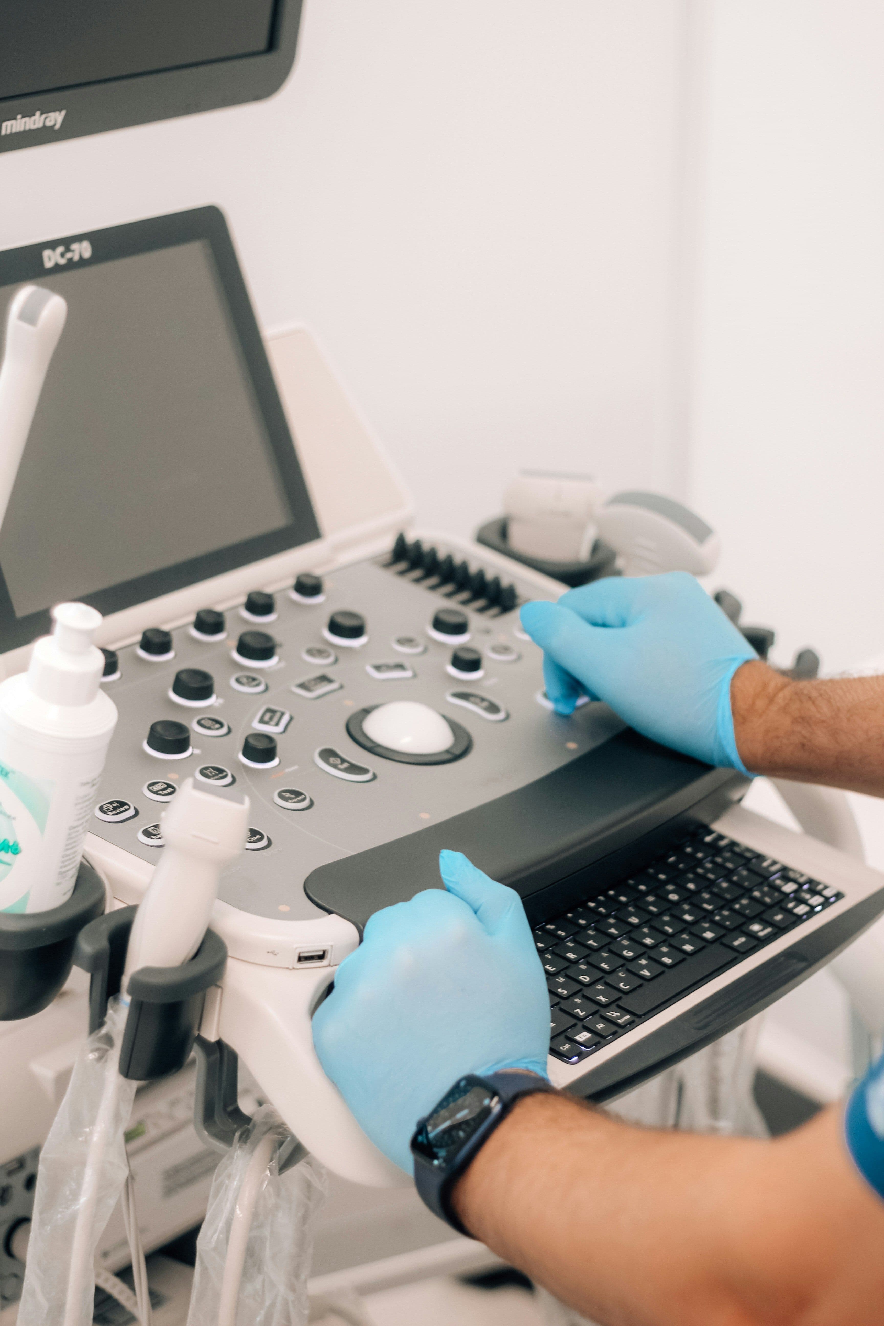 a man wearing blue gloves is working on a mindray ultrasound machine
