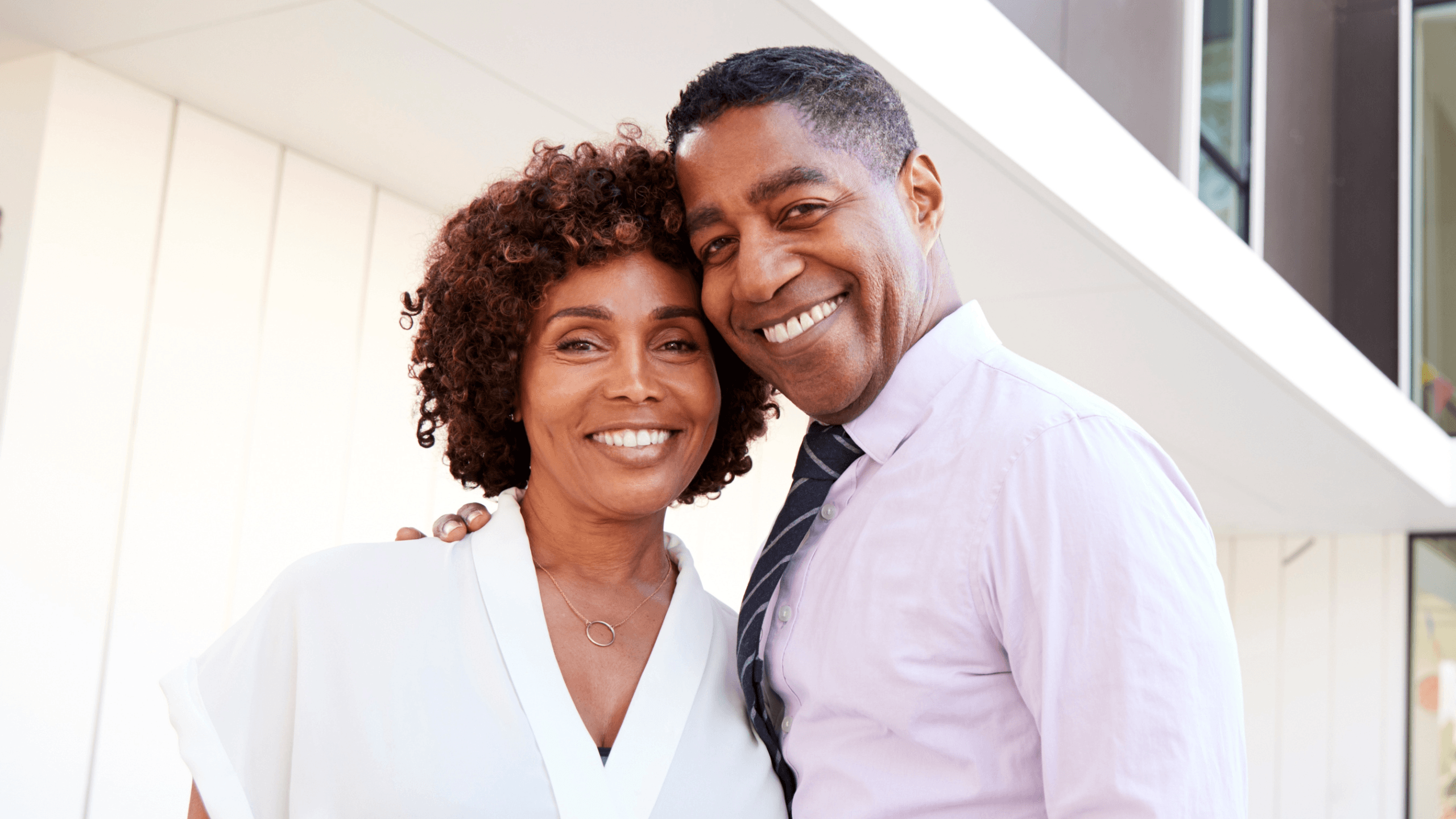 a man and woman are posing for a picture in front of a building