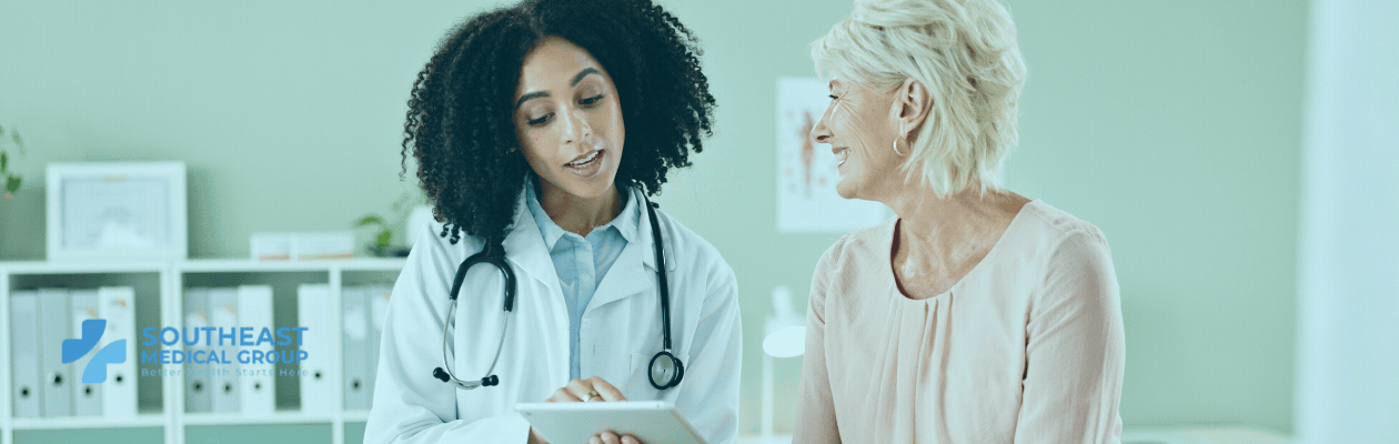 A female doctor shows a tablet to a smiling older female patient, with the Southeast Medical Group logo.