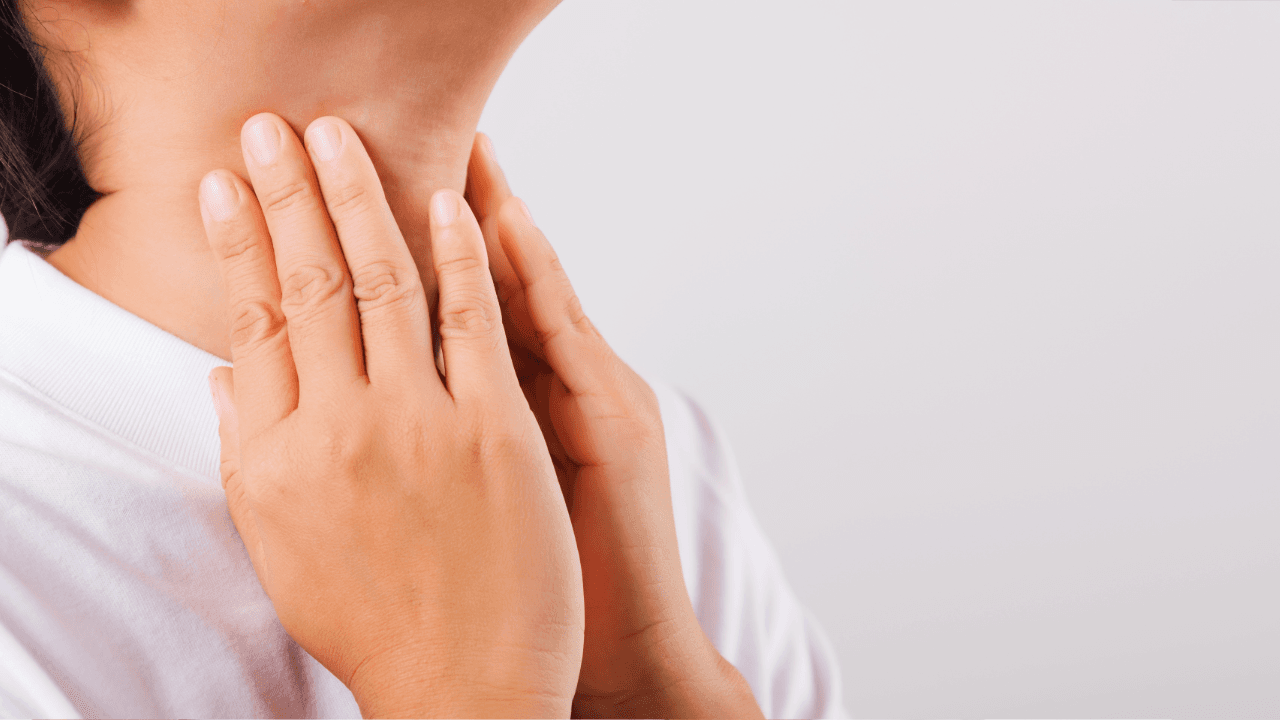 a woman in a white shirt is holding her thyroid with her hands