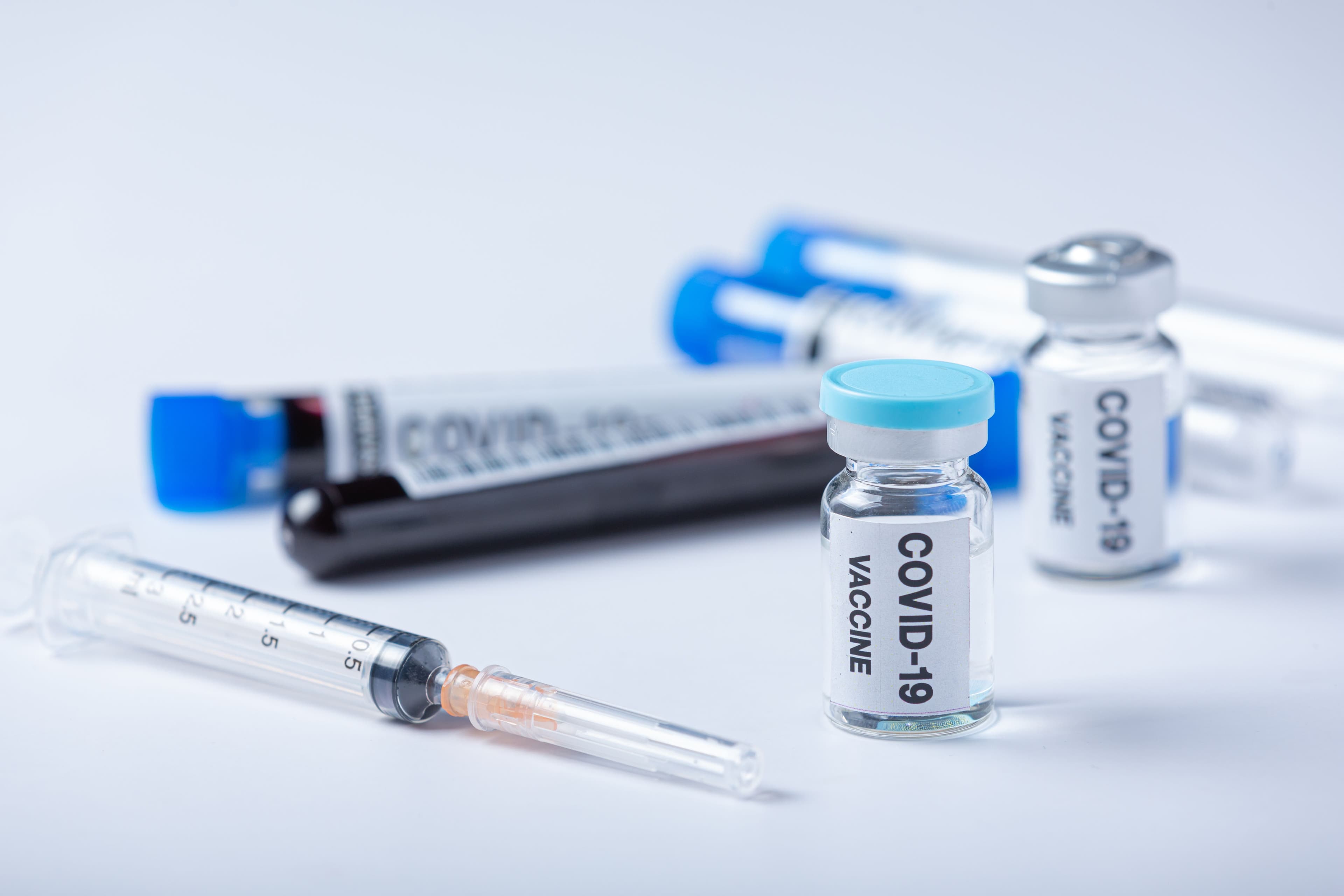 covid-19 vaccine and a syringe on a table .