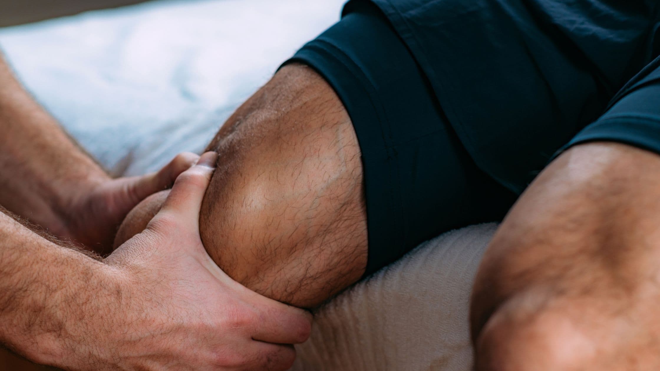a man is getting a massage on his leg while laying on a bed .