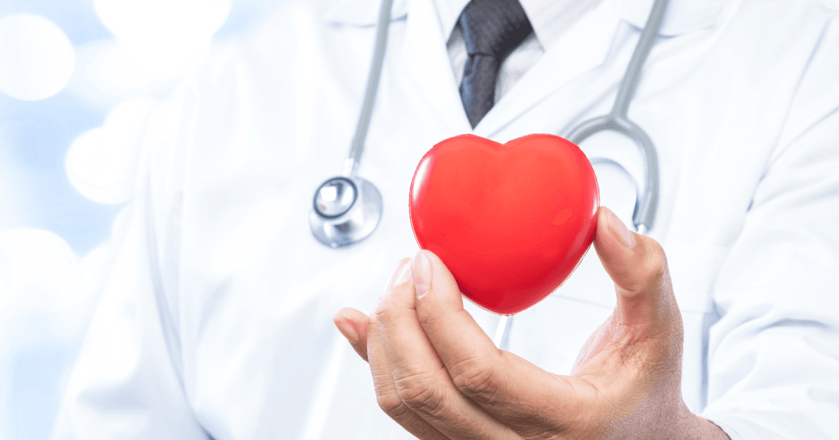 a doctor holding a red heart with a stethoscope around his neck