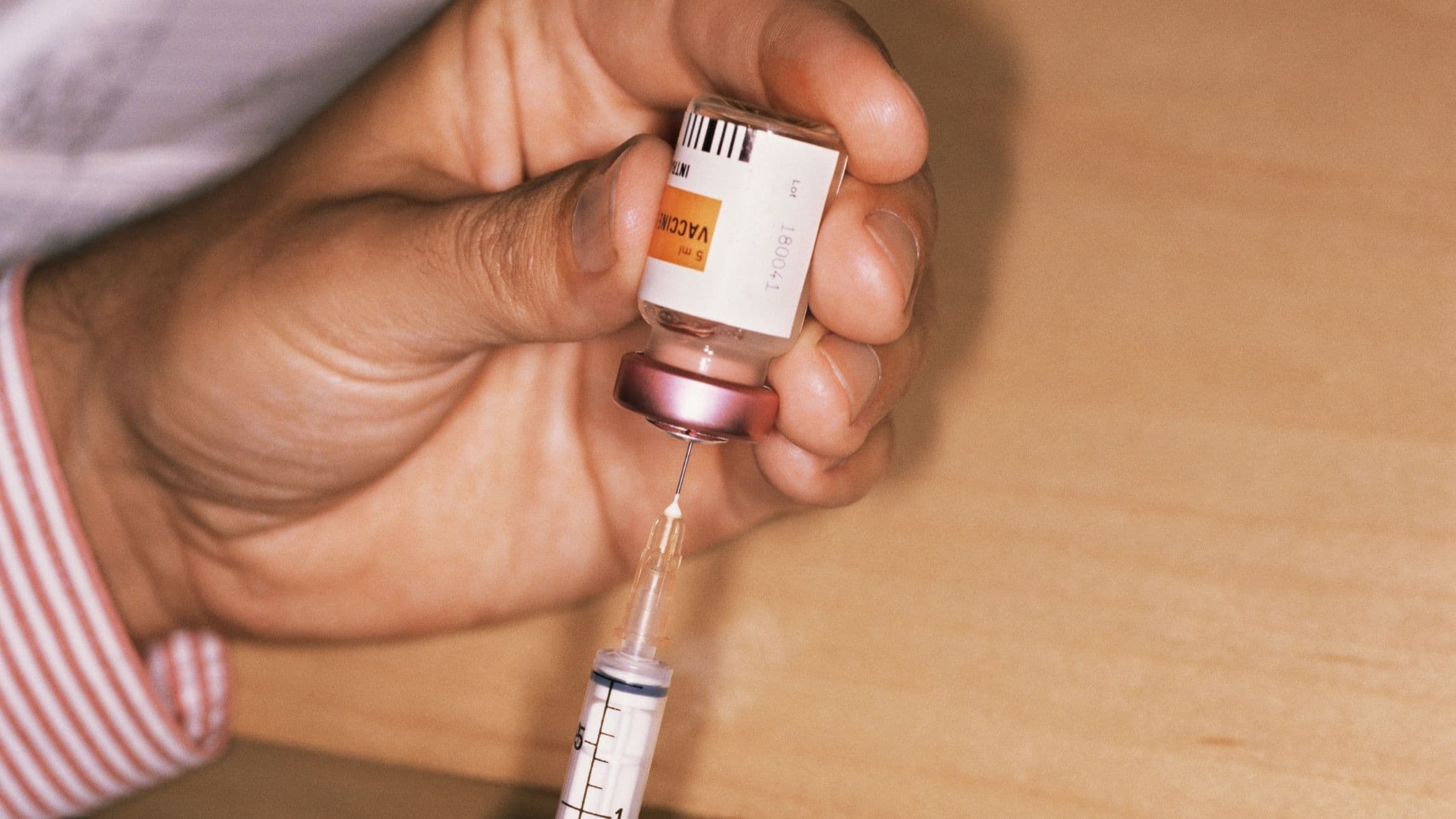 a person is holding a bottle of vaccine and a syringe .