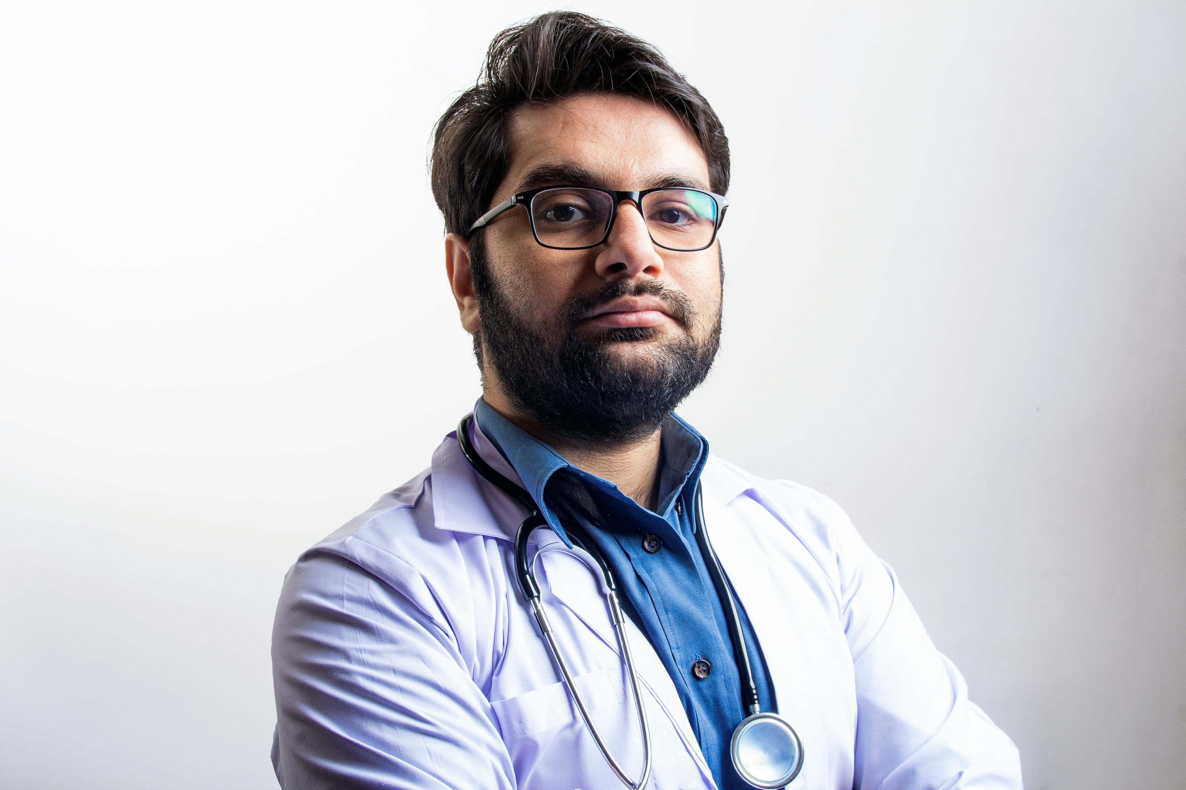 the doctor is wearing glasses and a stethoscope around his neck .