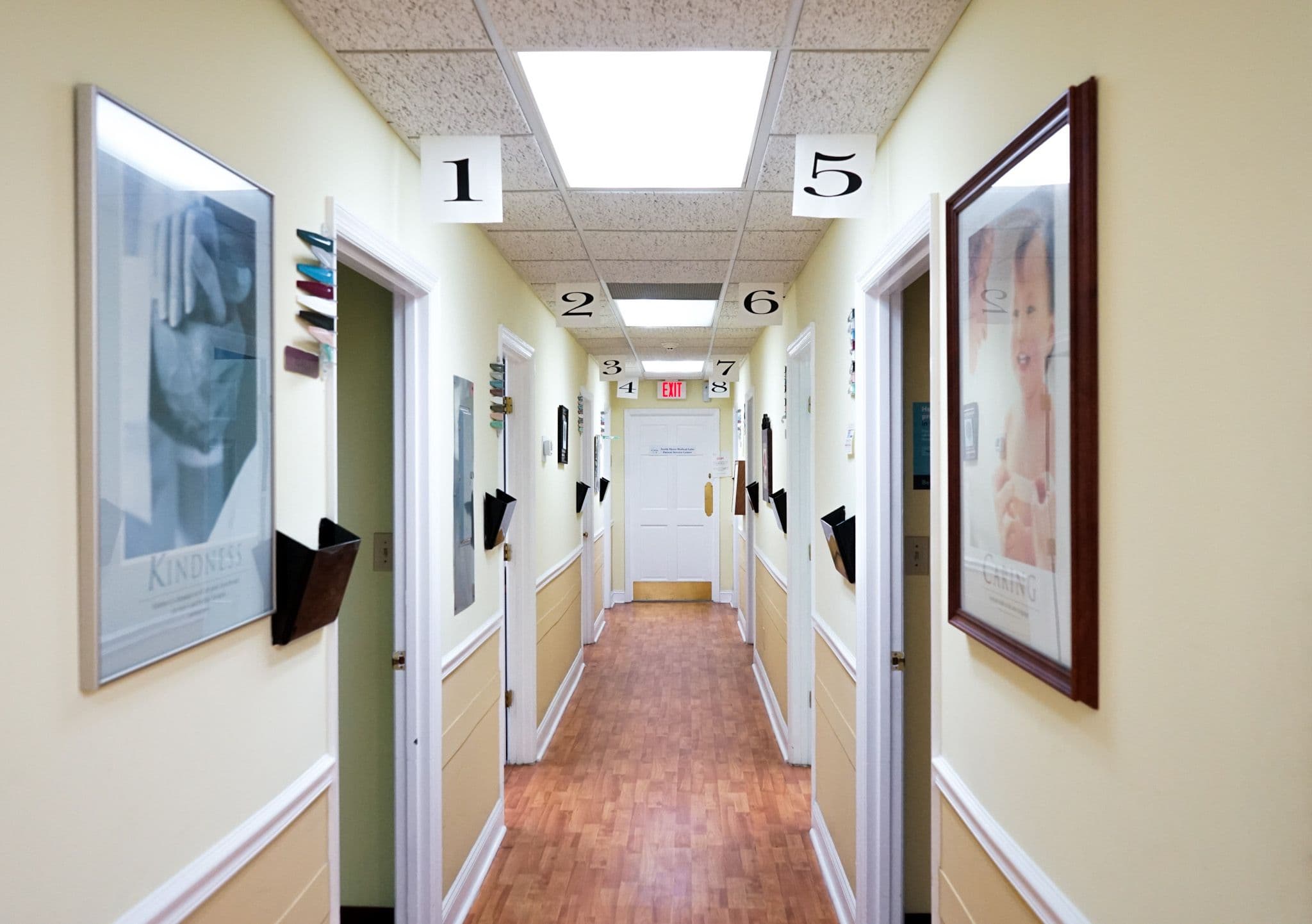a long hallway with a lot of doors and pictures on the wall .