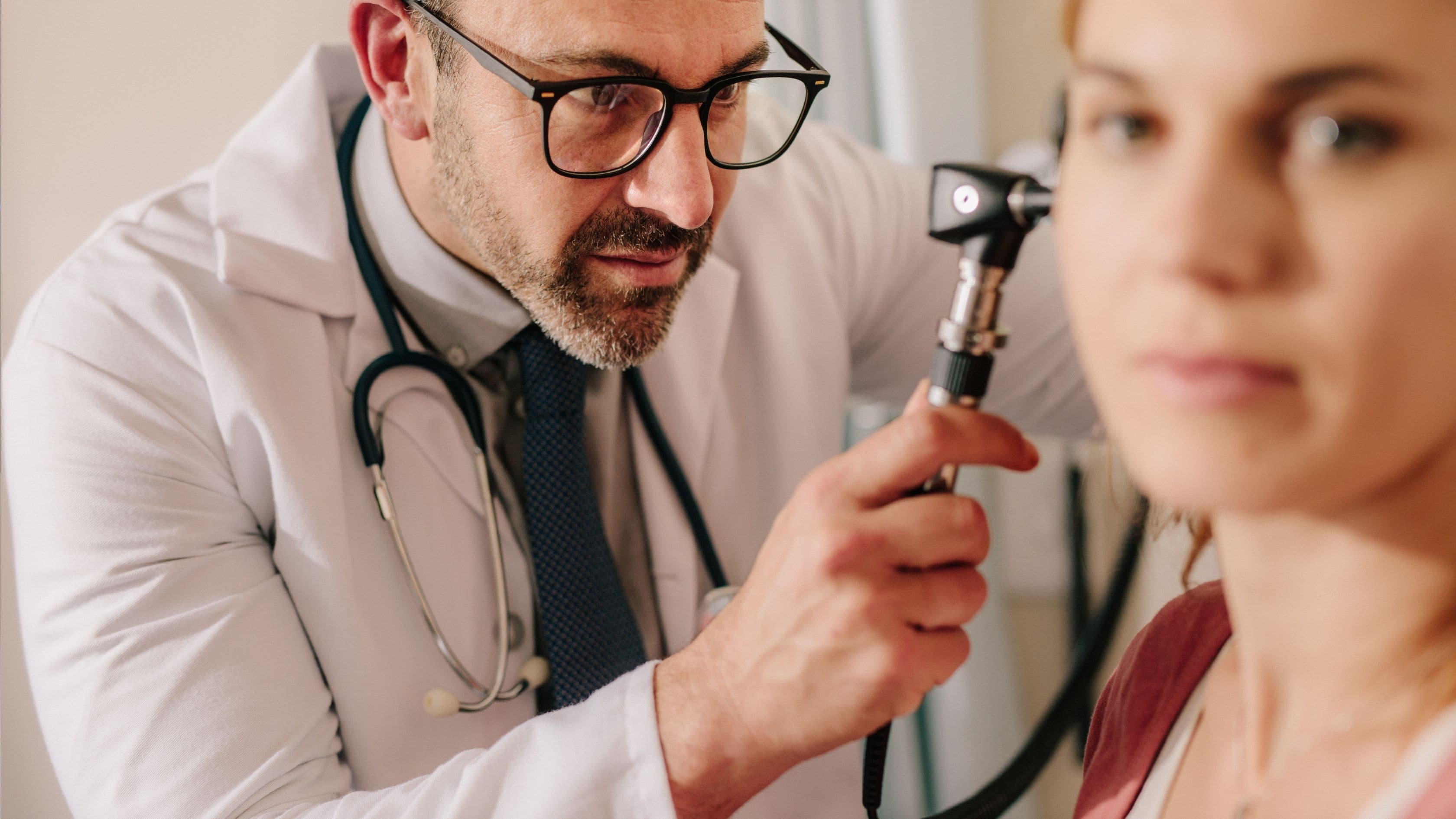 a doctor is examining a woman 's ear with a stethoscope .