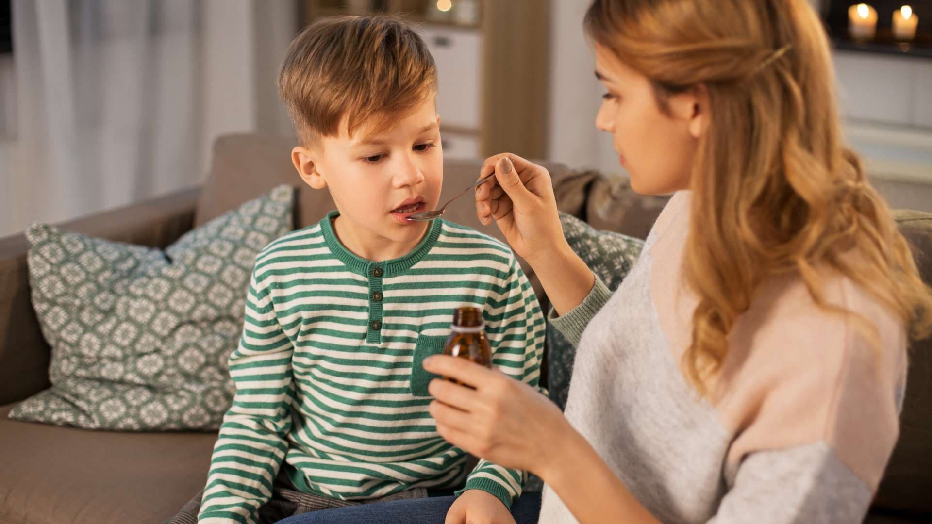 a woman is giving a child a syrup from a bottle .