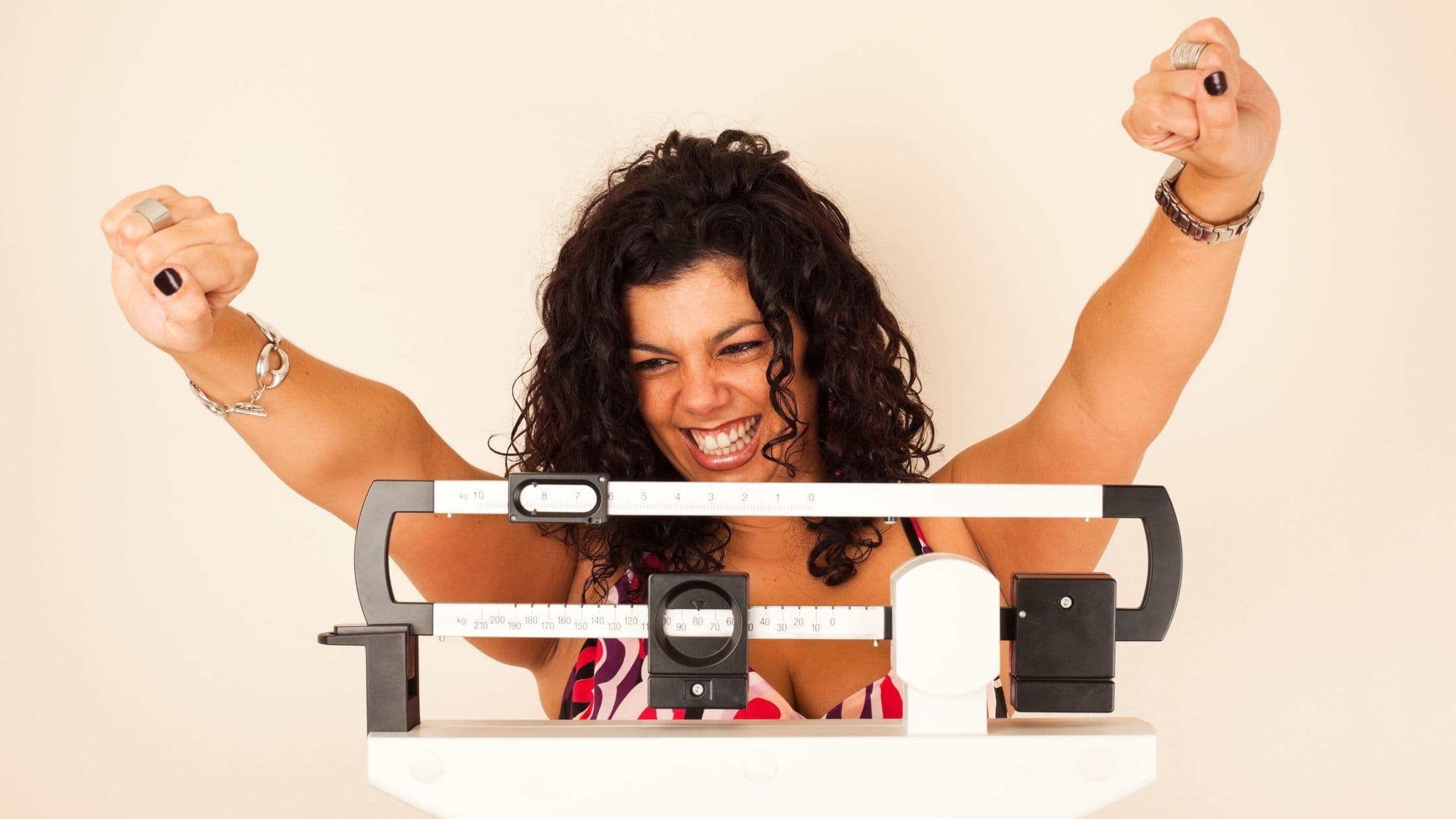 a woman is standing on a scale with her arms in the air .